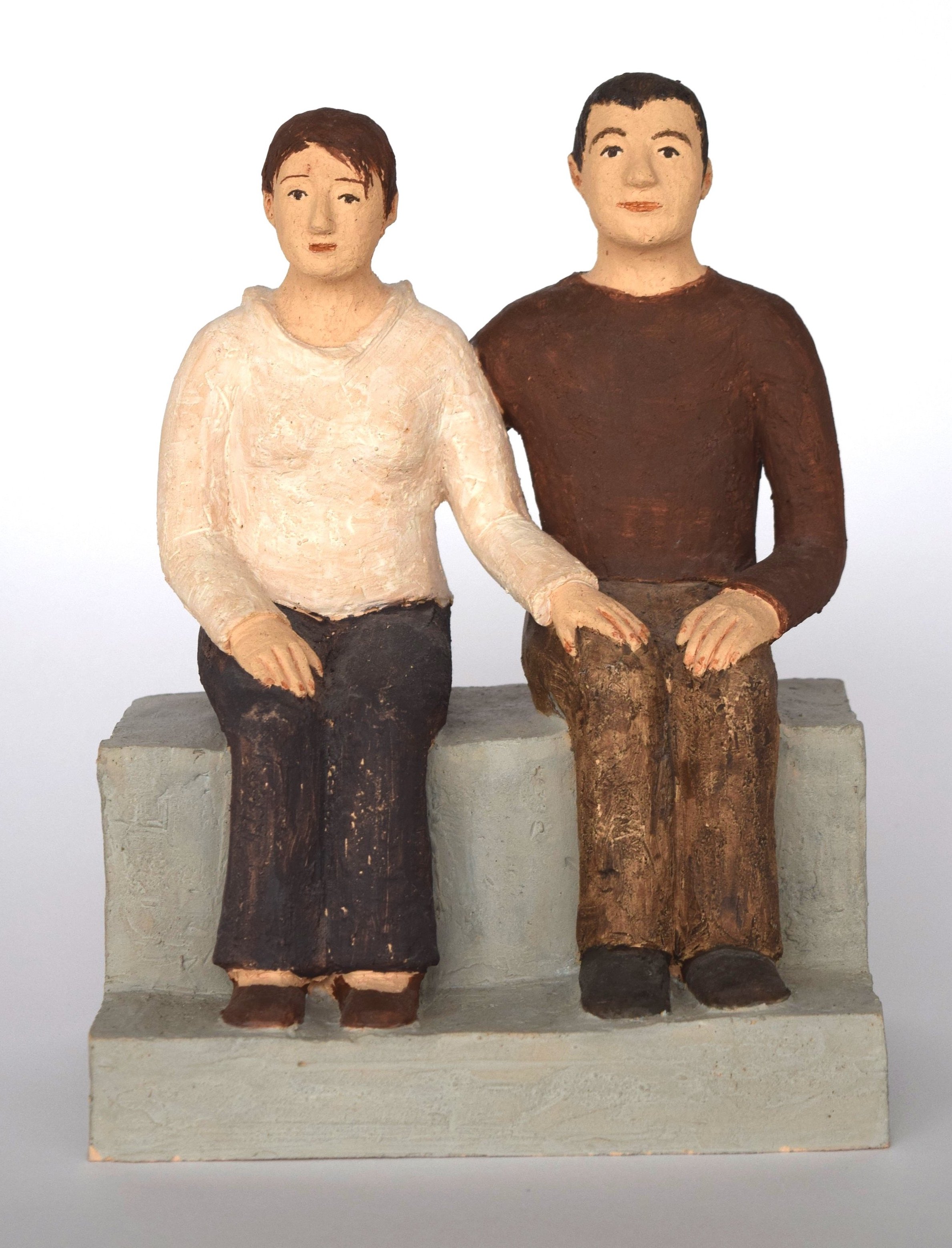 Holzskulptur eines sitzenden Paares, Mann und Frau auf einer Bank sitzend, mit einfacher Kleidung.