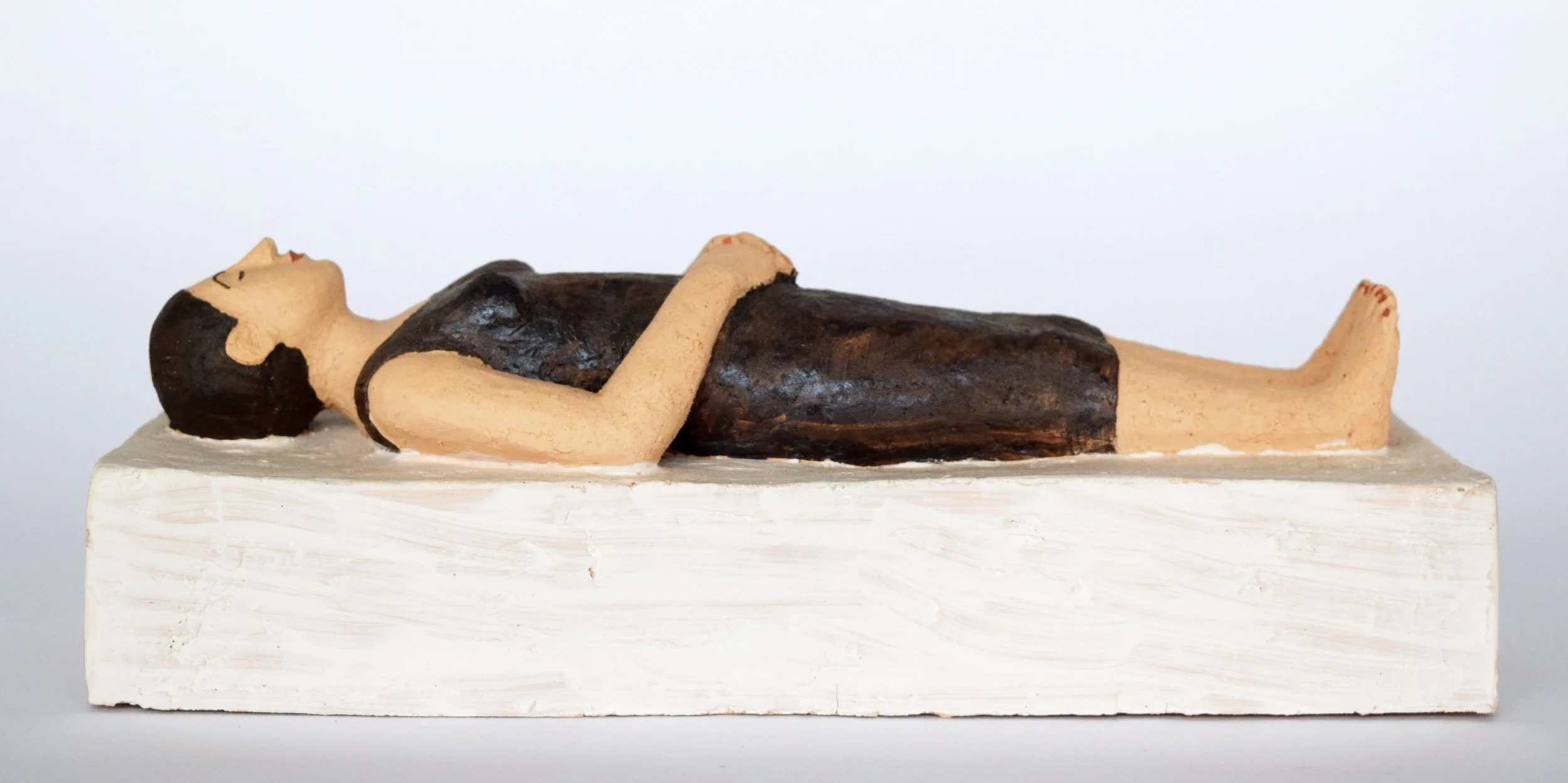 Tonfigur einer liegenden Frau auf einem rechteckigen Podest