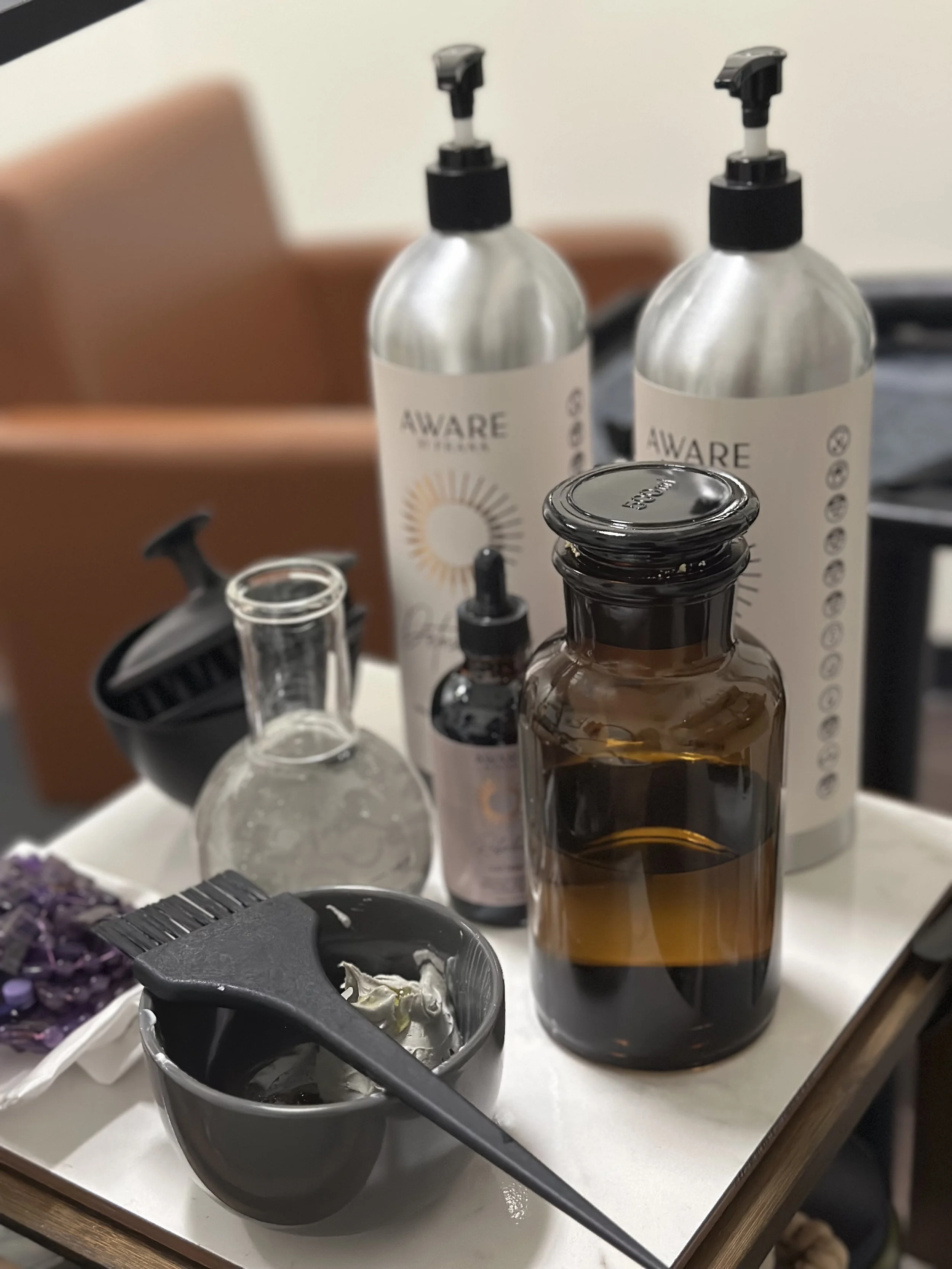 Holistic scalp care setup featuring AWARE by Prana products at Thousand Petals Holistic Beauty. This eco-luxury head spa treatment blends Ayurvedic wisdom, and scalp-balancing botanicals to promote a healthy microbiome for radiant hair growth. 