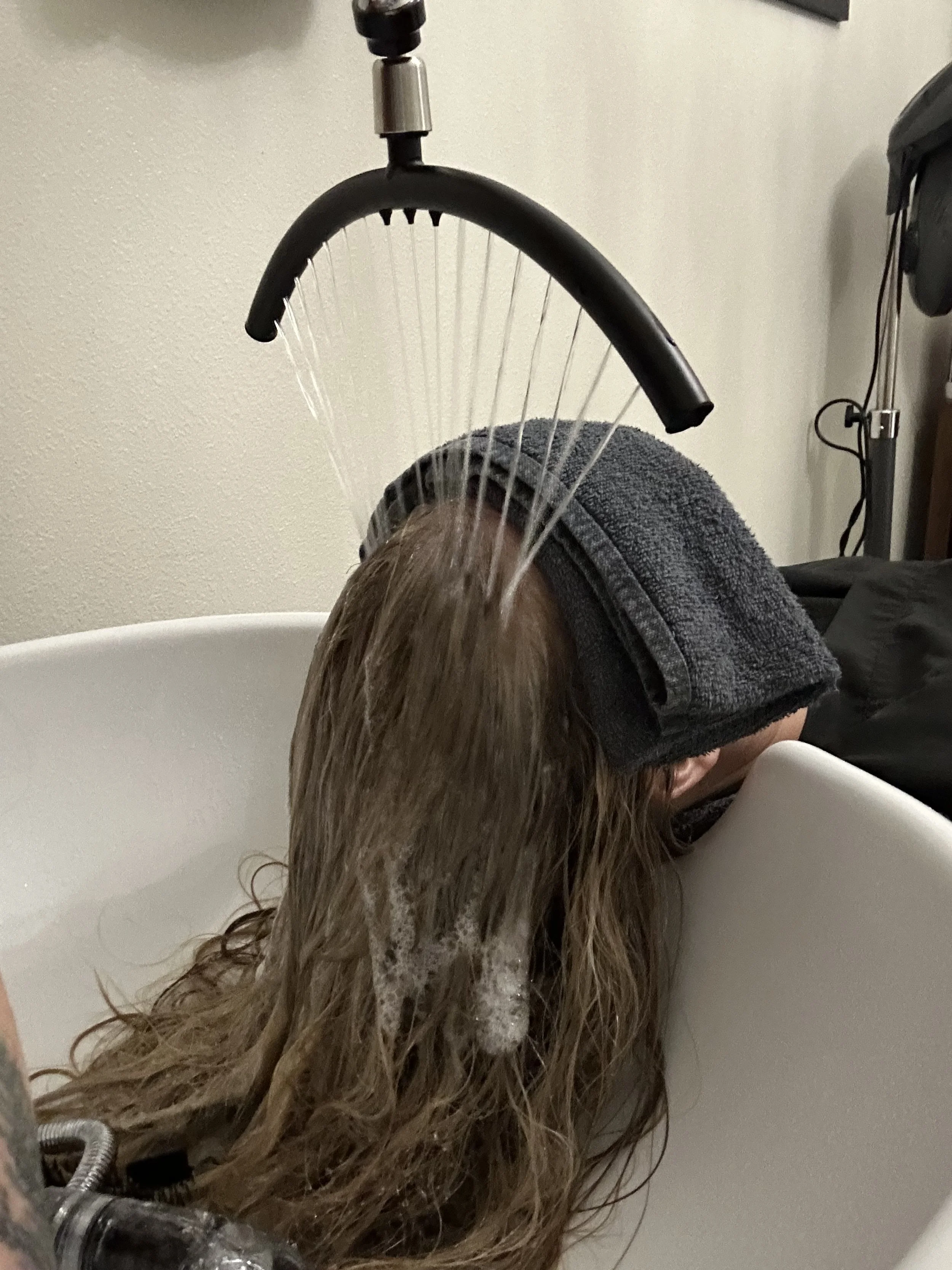 Client receiving a calming waterfall rinse at Thousand Petals Holistic Beauty- soothing the senses and helping the nervous system drop into deeper relaxation. This gentle rinse supports a healthy scalp environment by relieving stress and tension. 