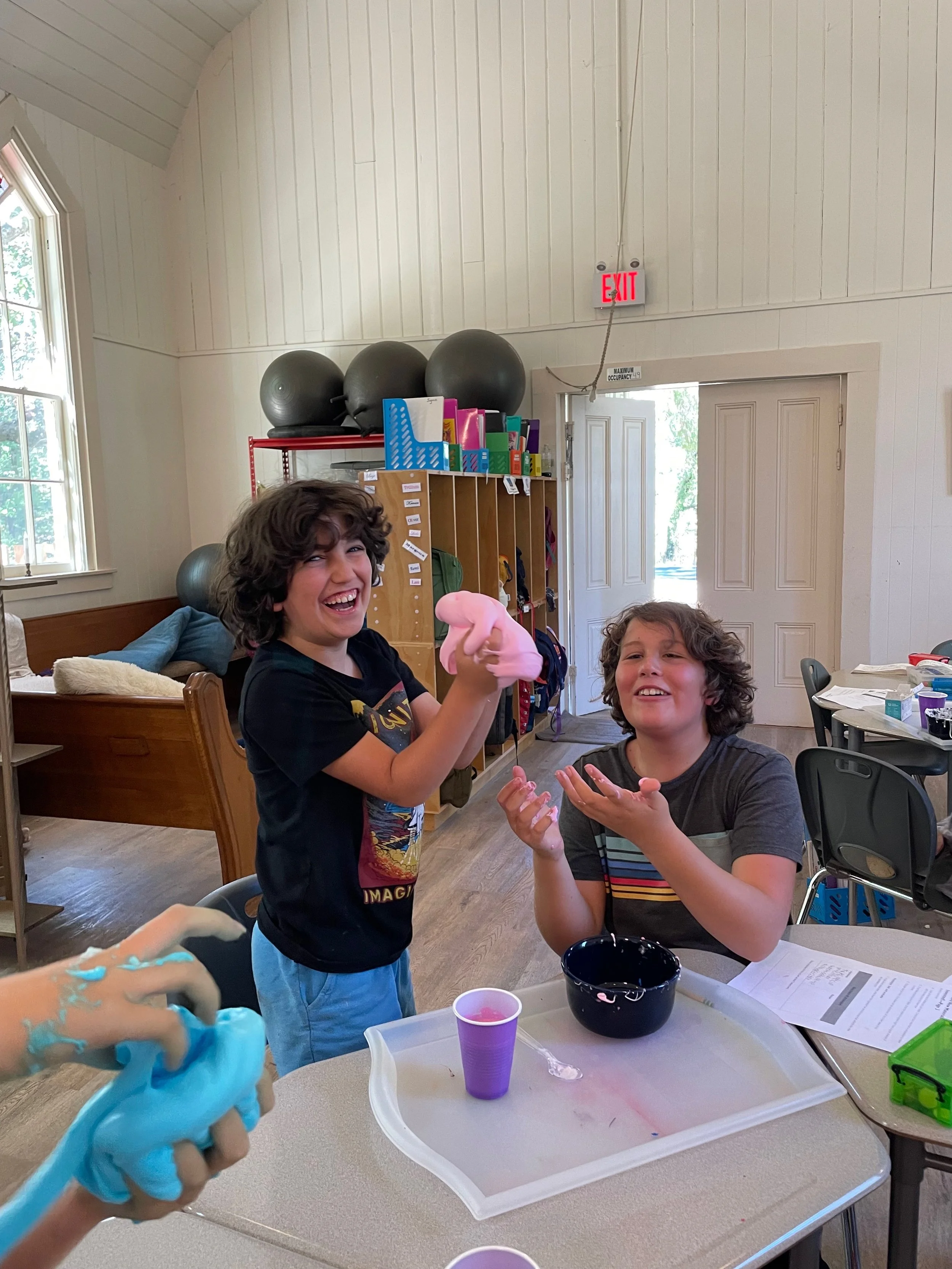 Two children in a classroom playing with slime.
