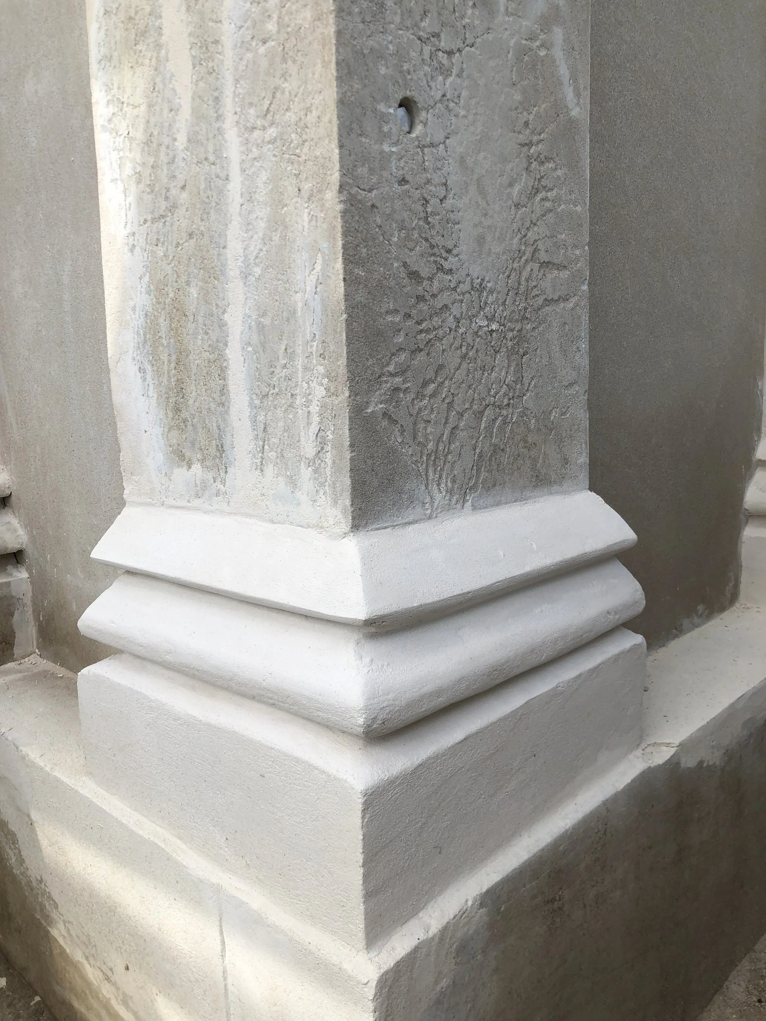 Close-up of a stone corner with a decorative white baseboard at the bottom, showing detailed texture and construction layers.