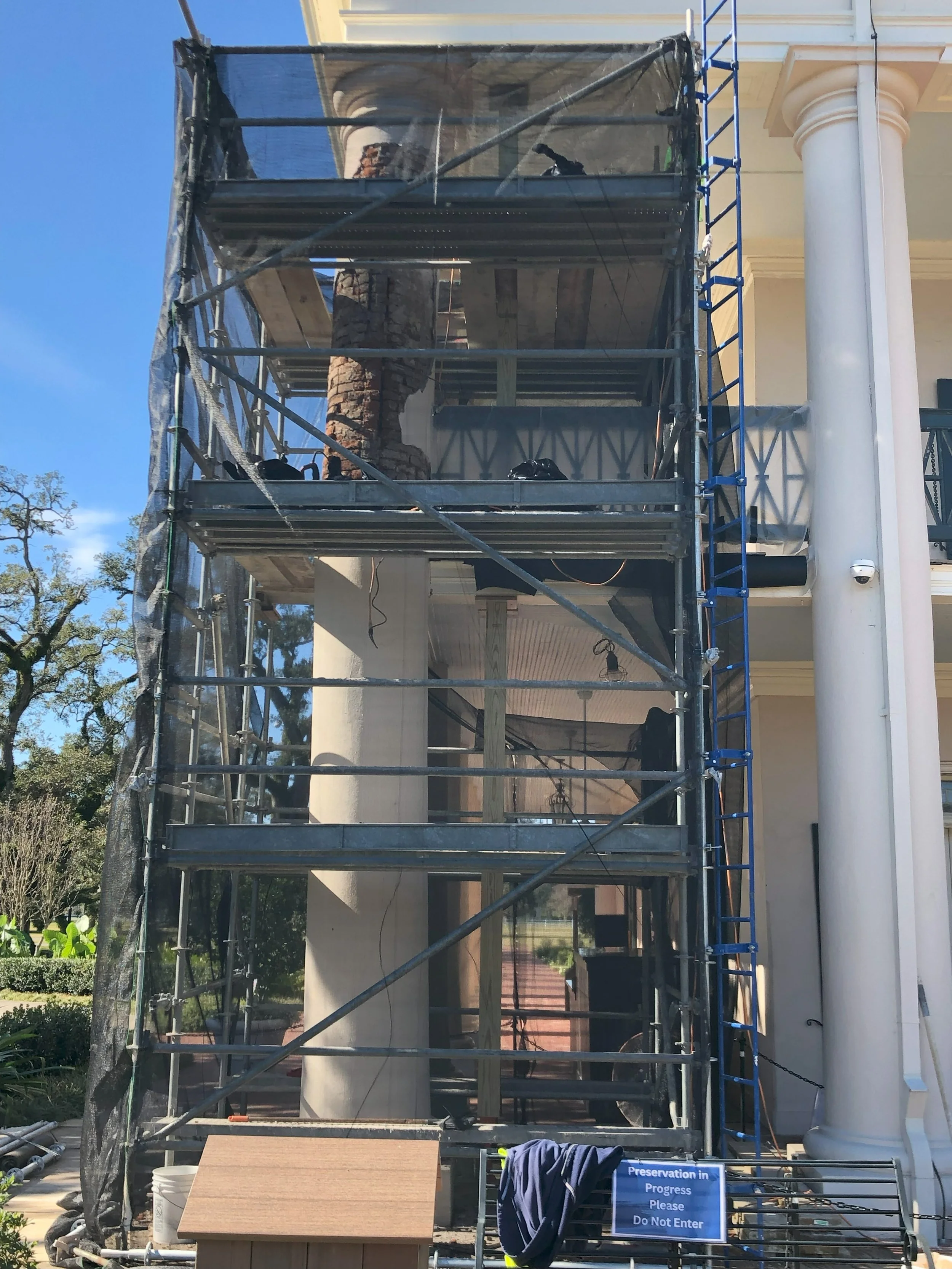 Scaffolding erected outside a building with a sign that reads 'Preservation in Progress. Please Do Not Enter.'