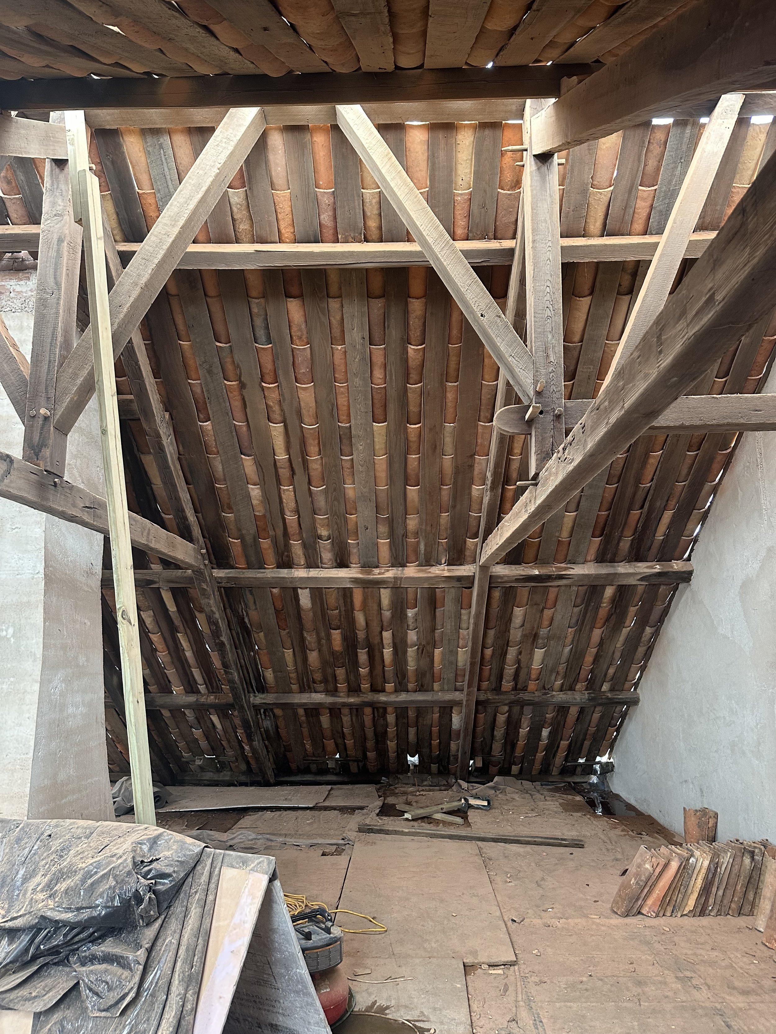 Constructed roof structure with wooden beams and terracotta tiles, in an attic or loft under renovation.