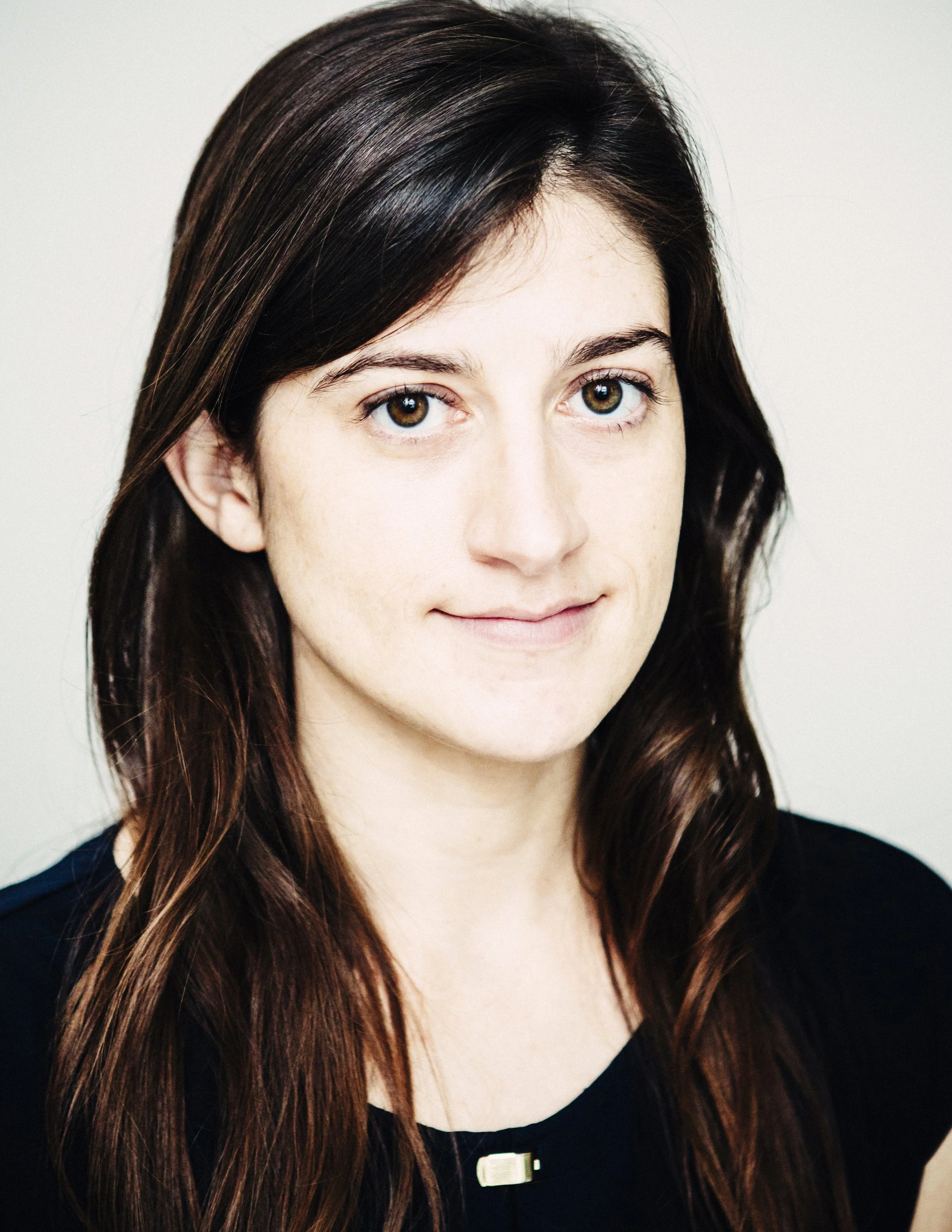 A young woman with long brown hair and brown eyes, wearing a black top, looking at the camera with a slight smile. Courtney Williams New Orleans.