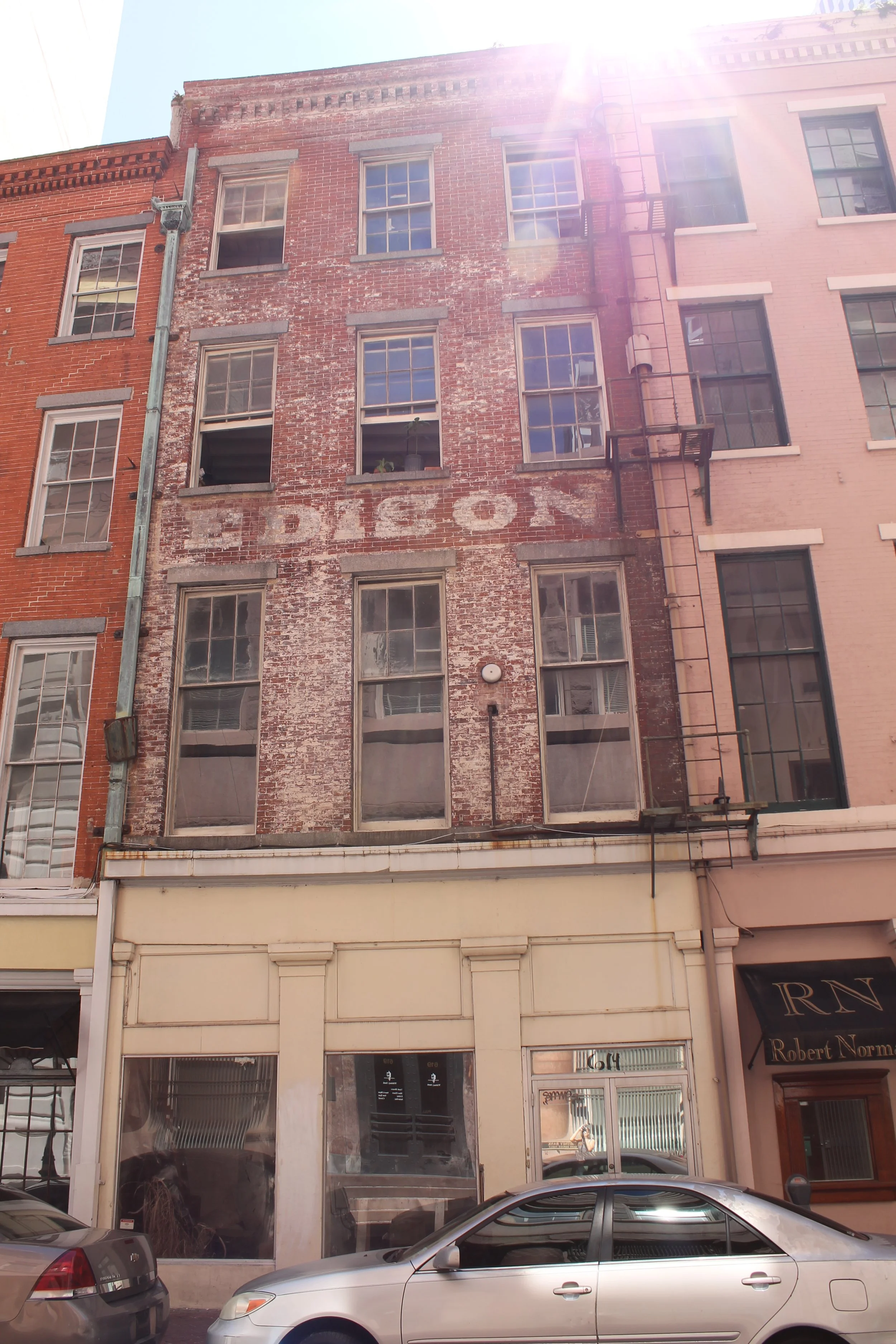 A multi-story brick building with old painted sign reading 'EDISON' on the facade, partially weathered.  Historic brick repair and brick restoration. New Orleans Cypress Building Conservation.