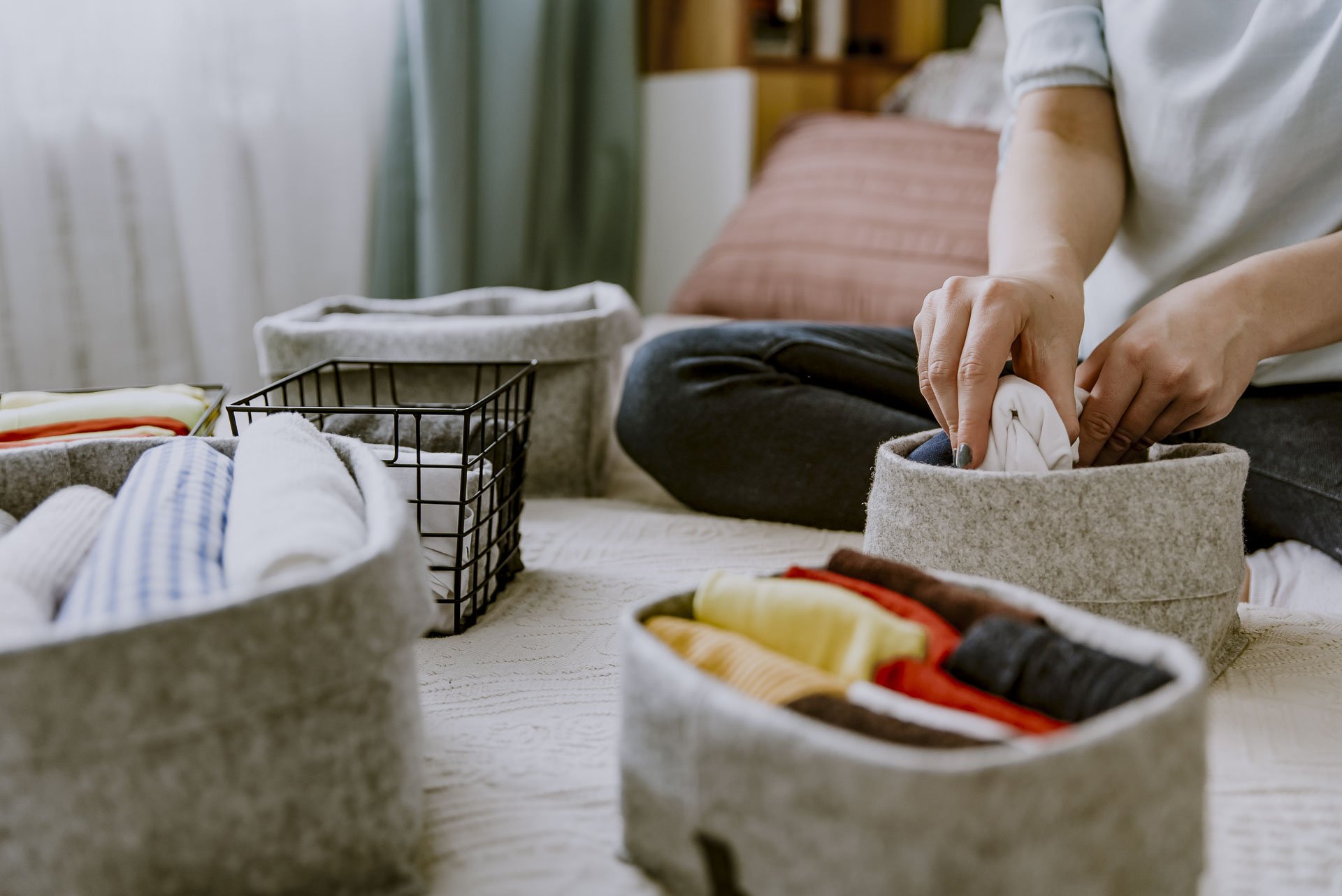 Home organizer folding clothes and placing them in storage bins