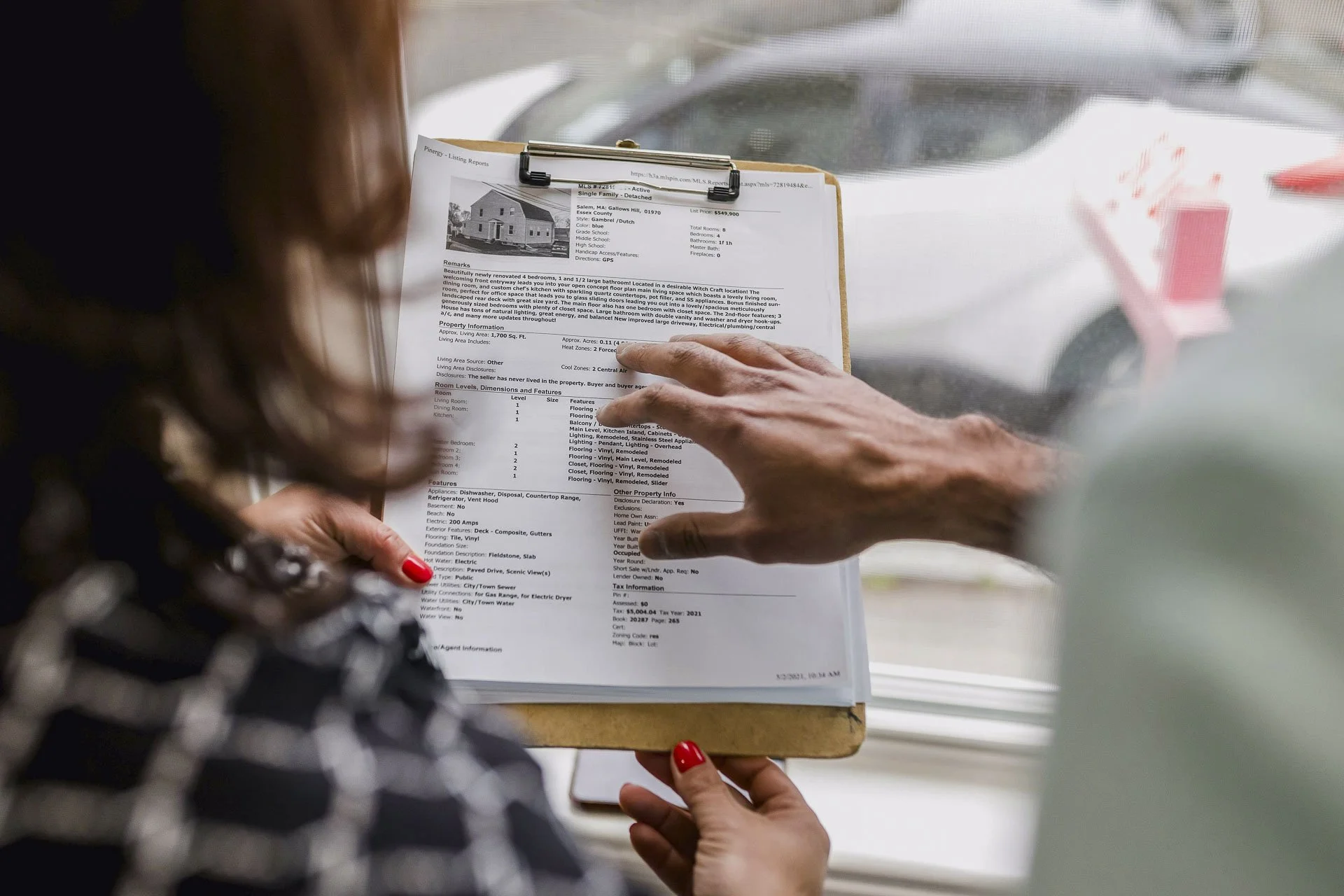 A couple looks at a home listing on a clipboard
