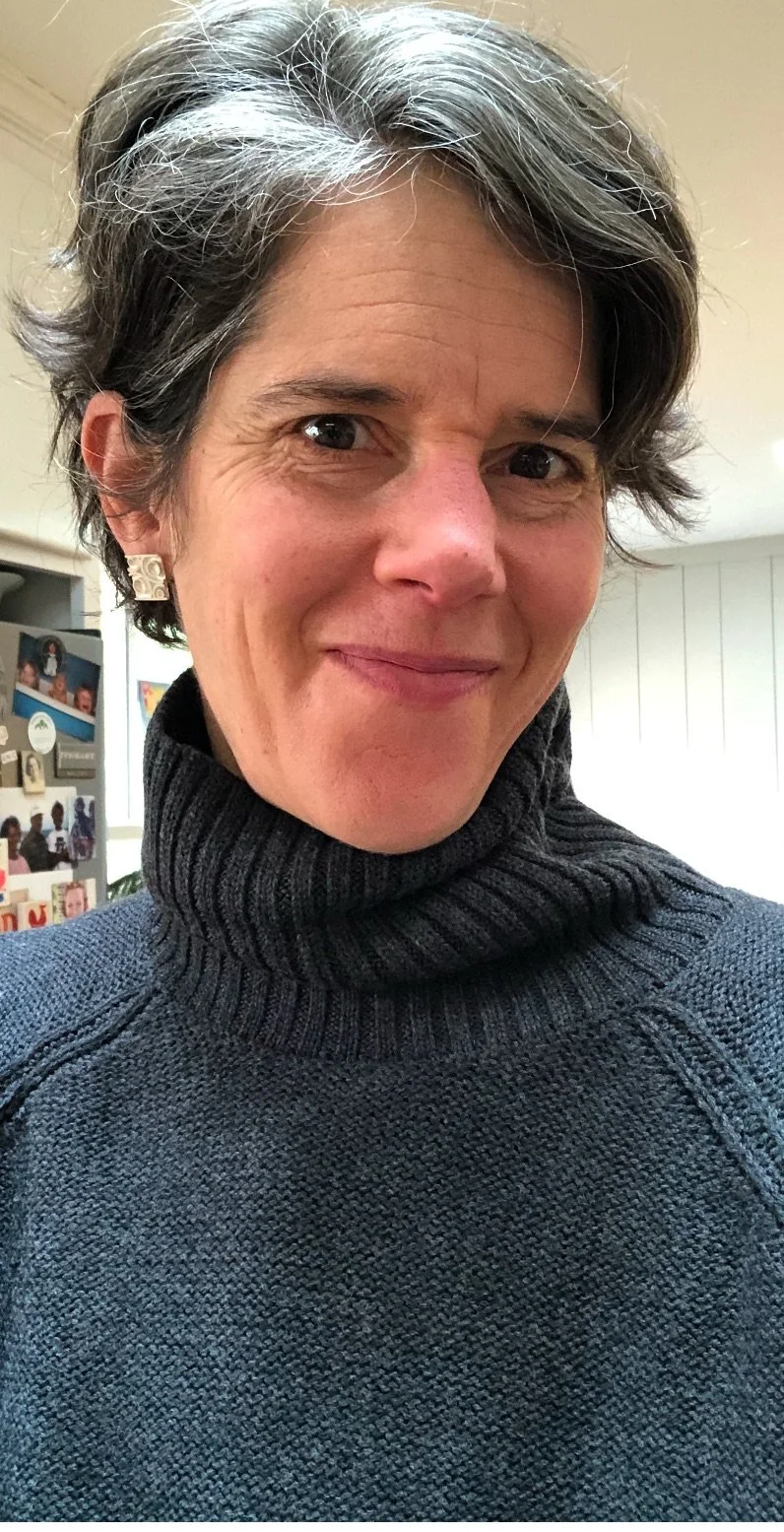 Person wearing a dark turtleneck sweater, smiling.