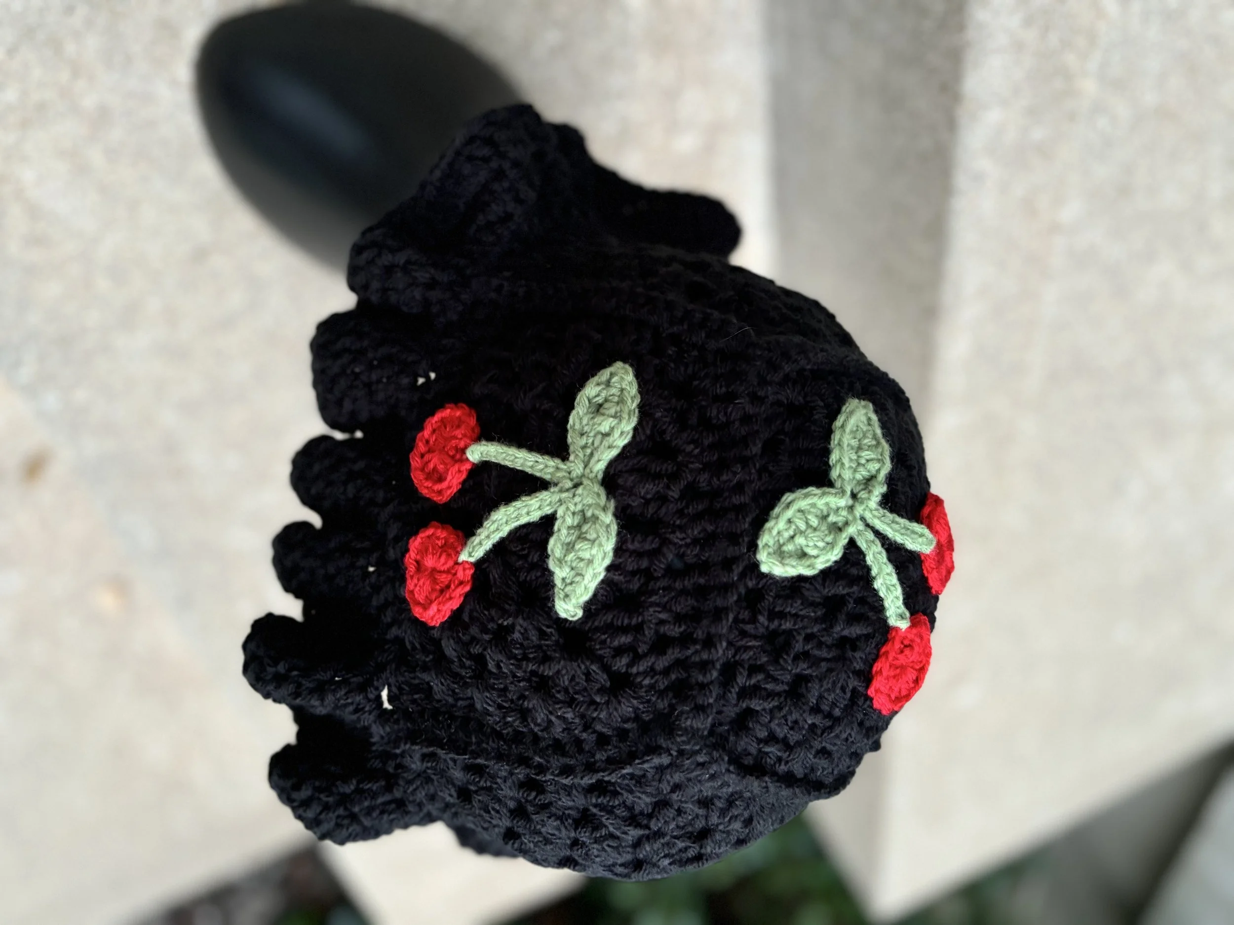 Crocheted black octopus with red and green cherry decorations