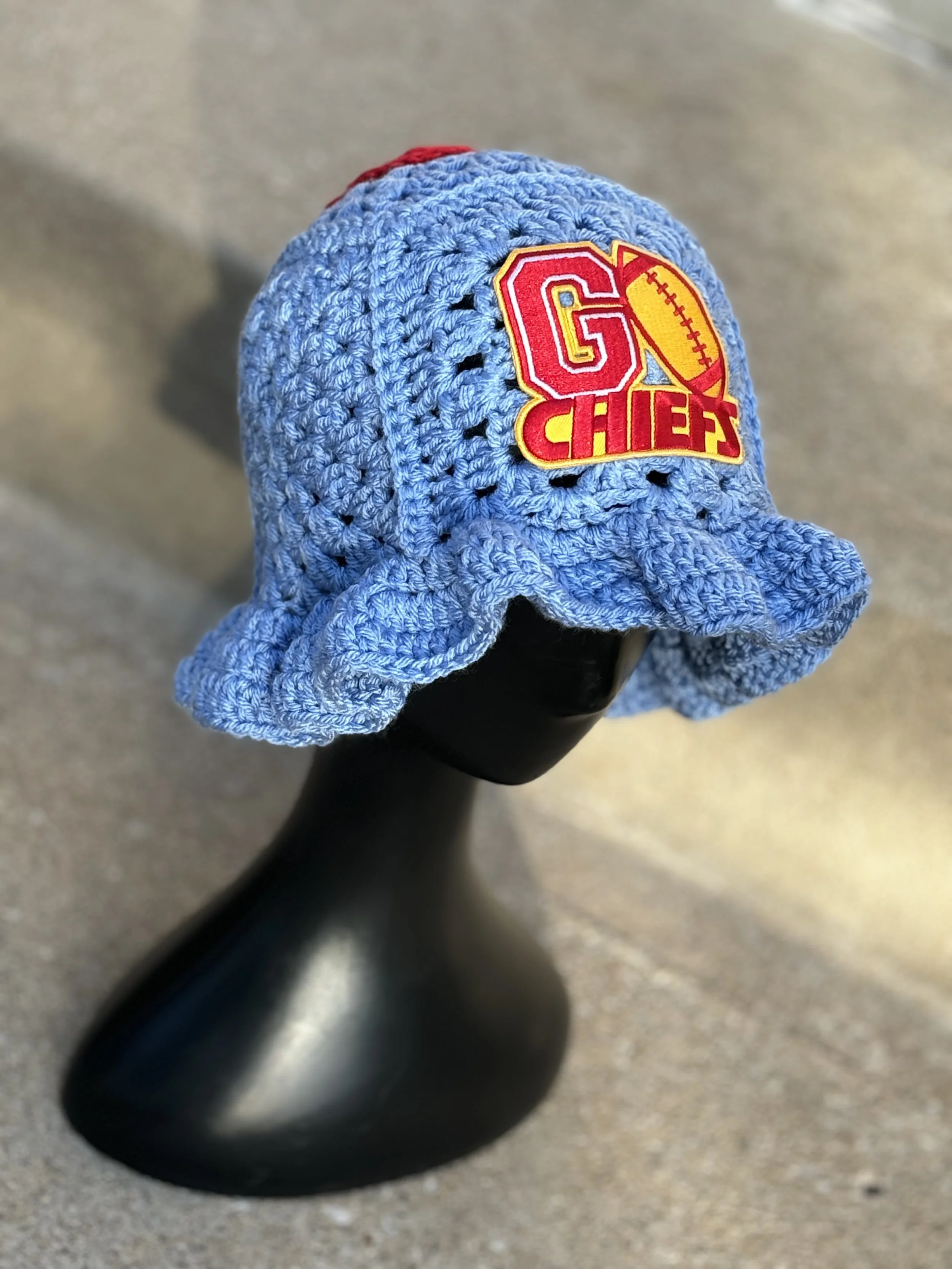 Light blue crocheted hat with "Go Chiefs" patch on mannequin head.