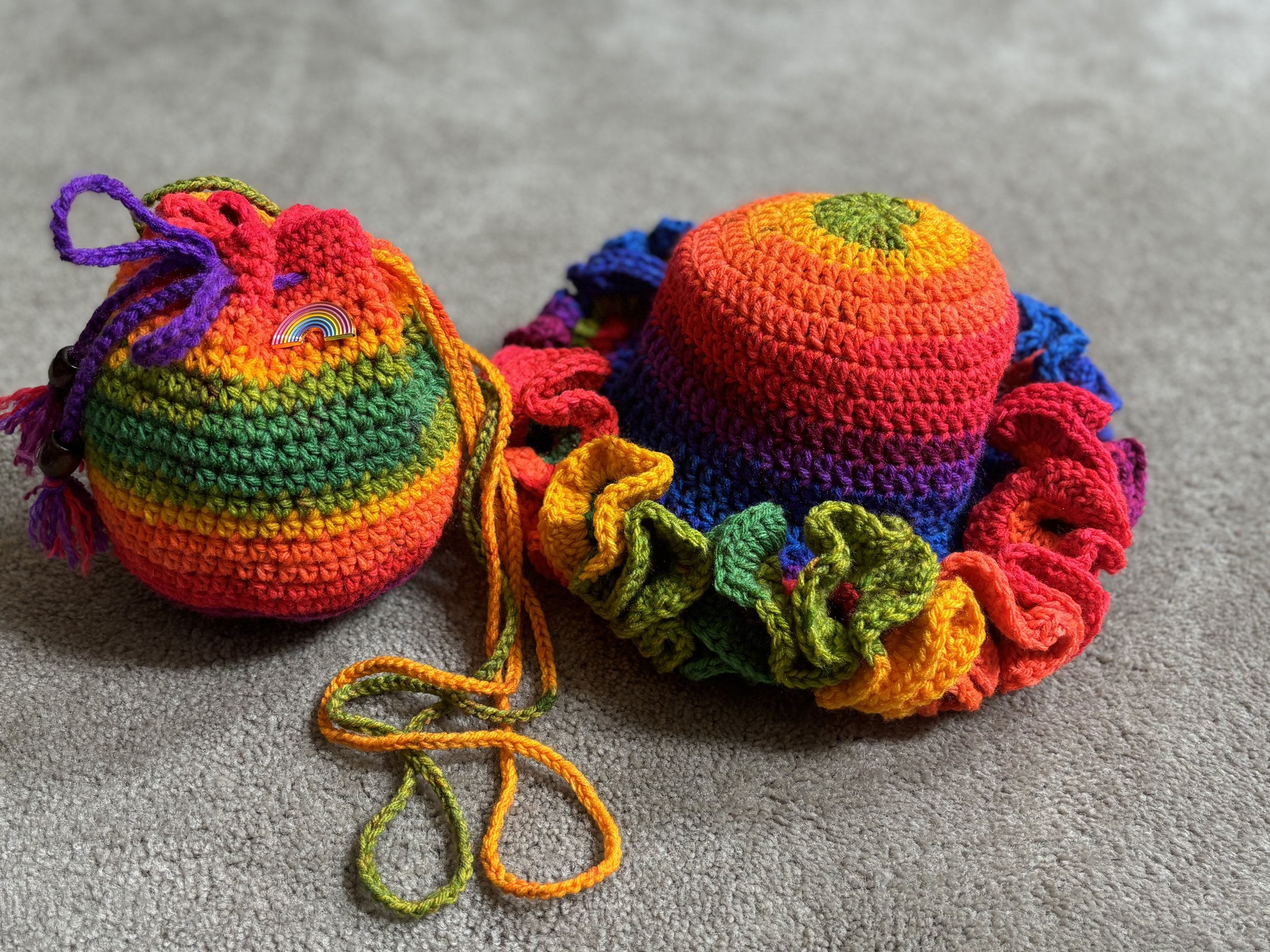 Colorful crocheted hat and drawstring bag on gray carpet