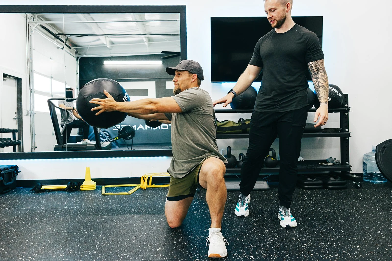 patient completing an exercise with a medicine ball under the guidance of a physical therapist