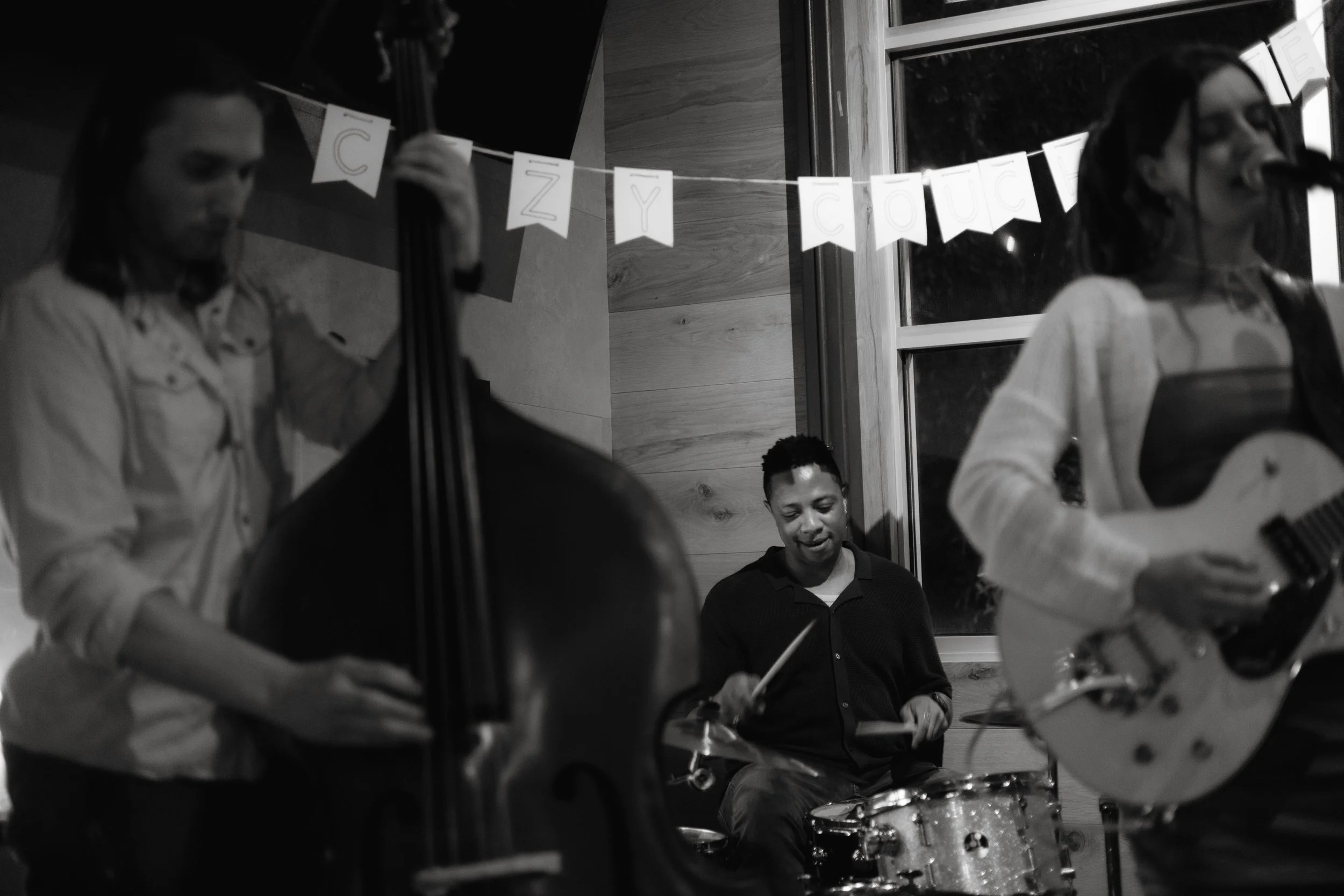 Musicians playing instruments at a birthday party, with a 'Happy Birthday' banner in the background.