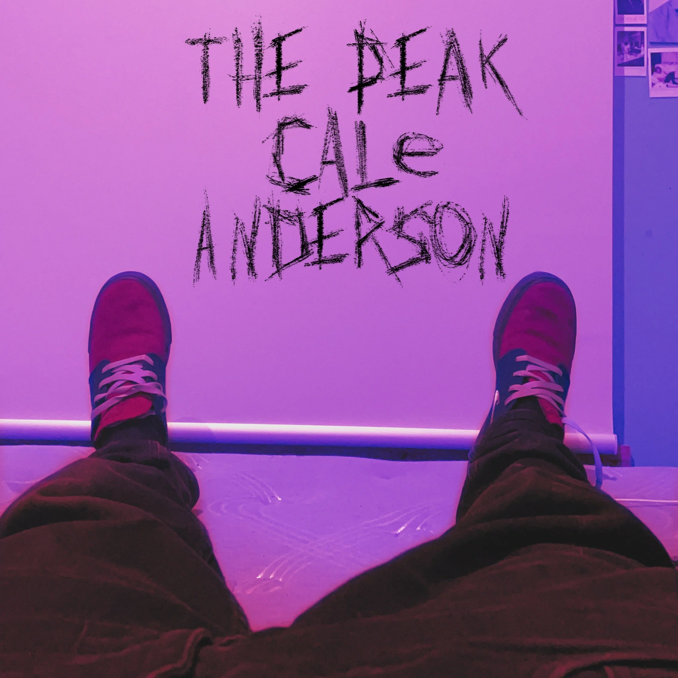 Person sitting with legs extended and wearing red sneakers, viewing a neon-lit sign with the text 'THE PEAK CAFE ANNEX' written in black, sketchy letters on a wall.