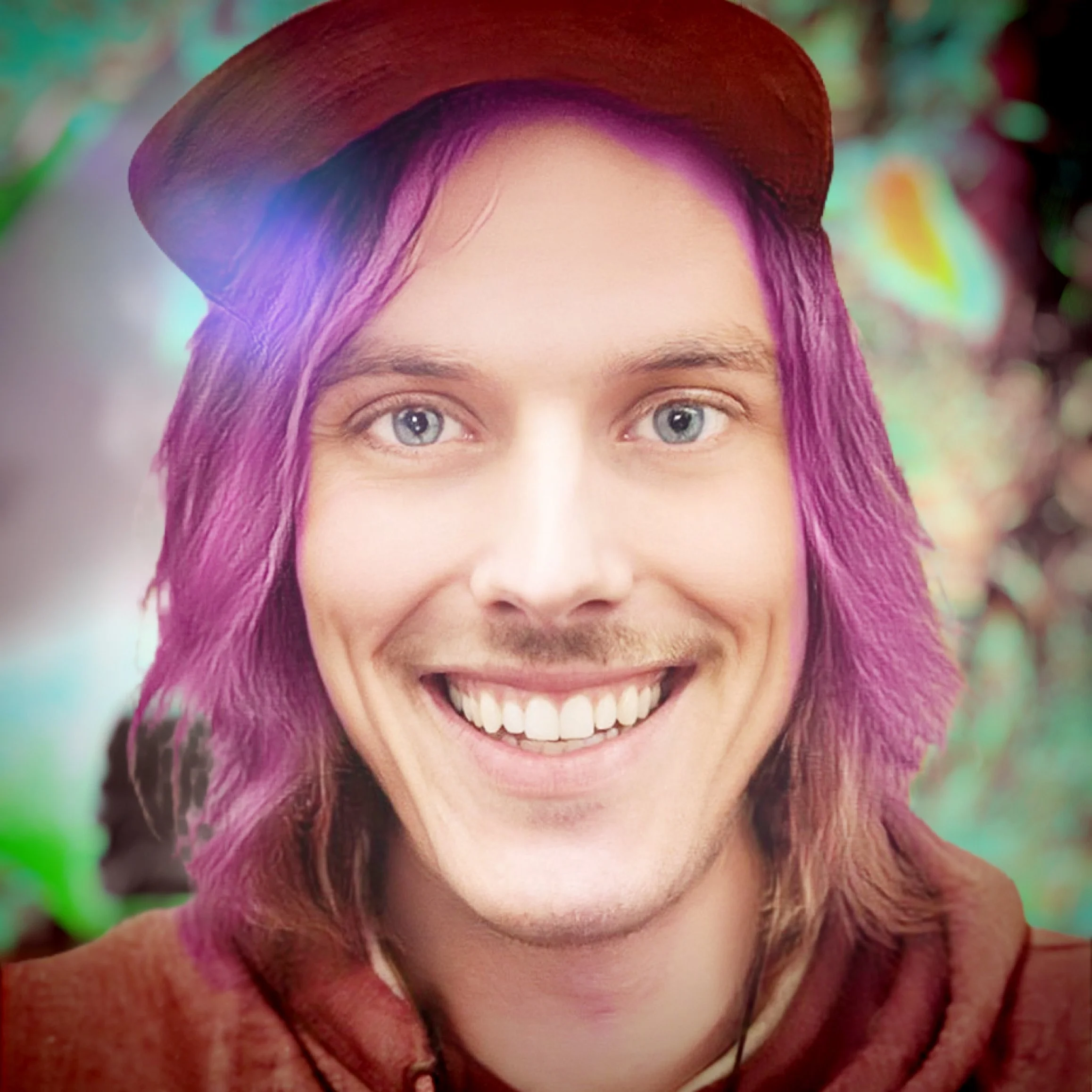 A person with bright pink hair, wearing a brown hat, smiling and looking at the camera.