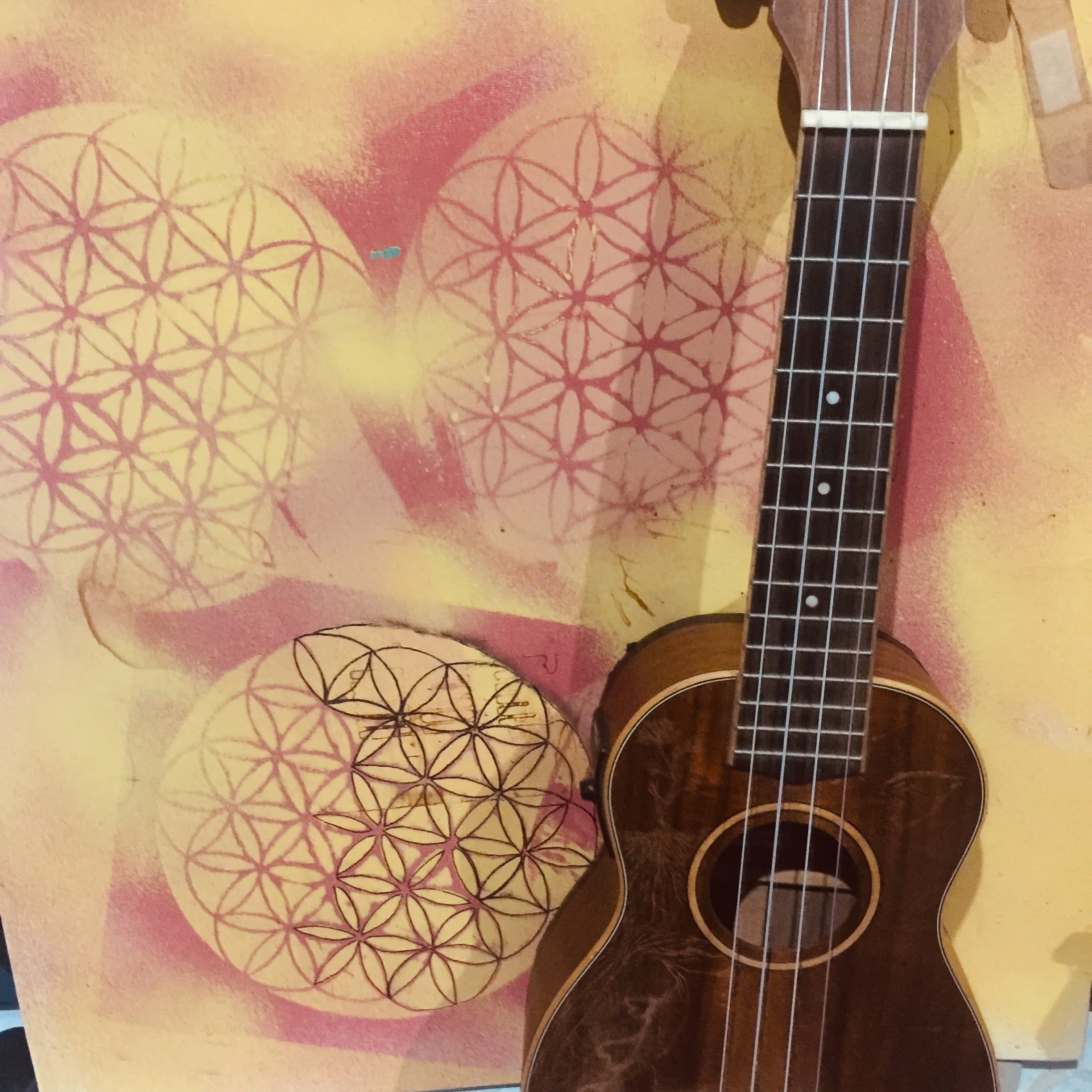 An acoustic guitar in front of a colorful wall with geometric designs.