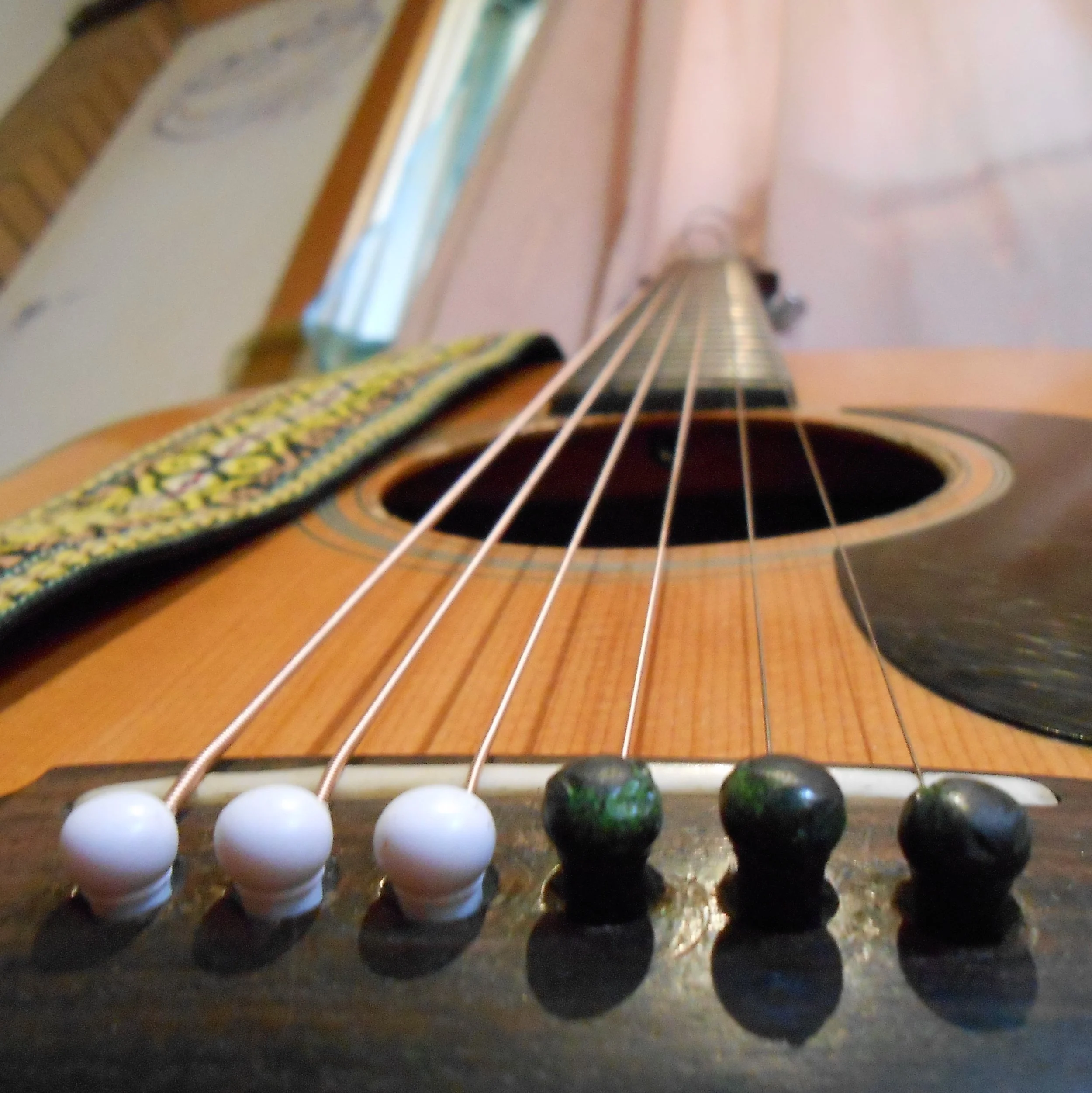 Close-up of an acoustic guitar, focusing on the strings and bridge.