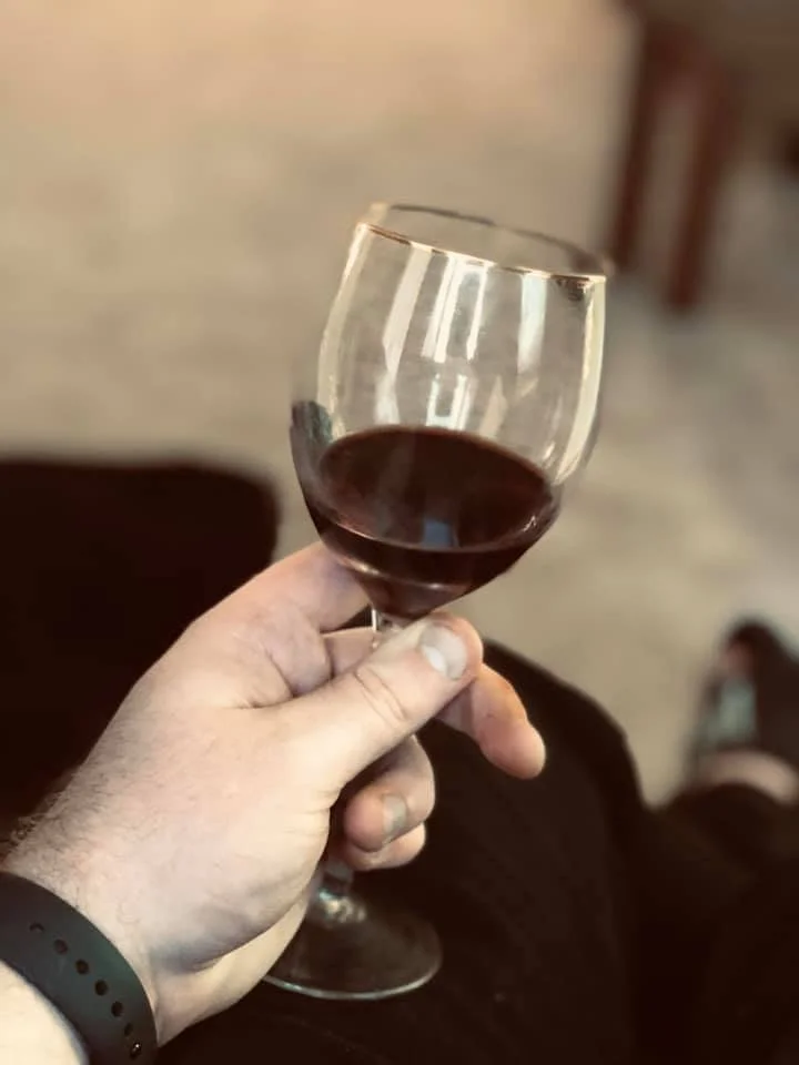 Close-up of a hand holding a glass of red wine.