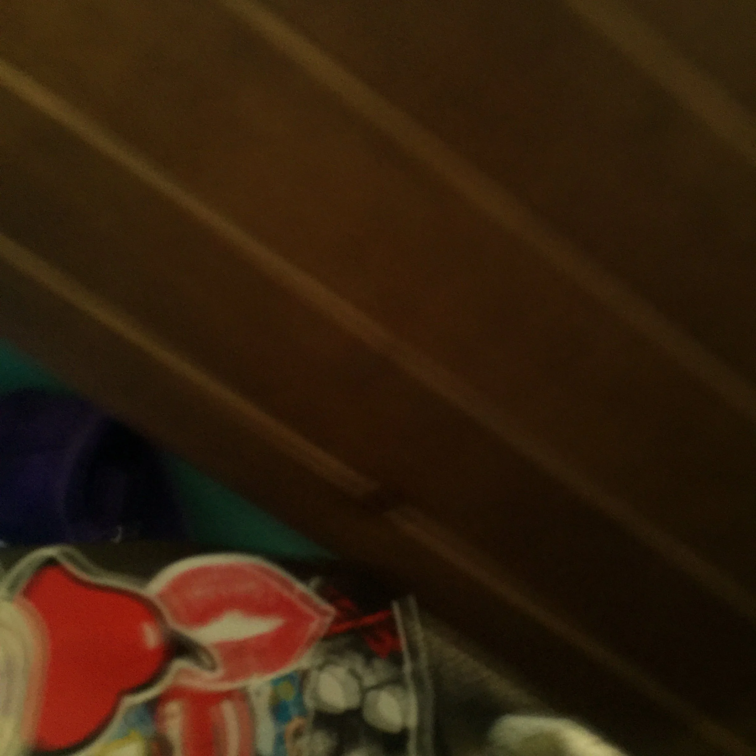 Part of a wooden surface and some colorful objects at the bottom, including a red and white item with some black and other colored details.