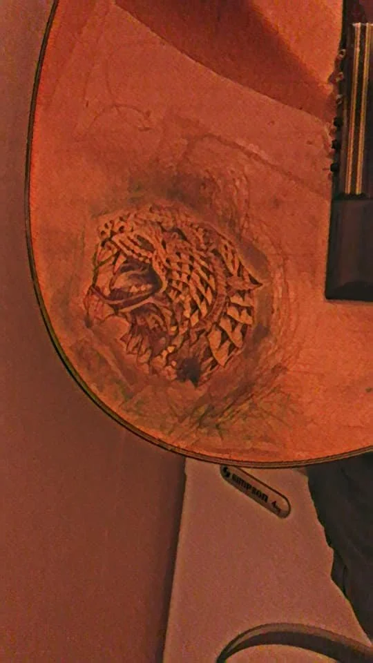 Inside of an acoustic guitar showing a detailed snake illustration painted or inlaid on the guitar's body.