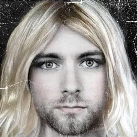 A black-and-white portrait of a man with long blonde hair, light eyes, and a beard, against a dark background.