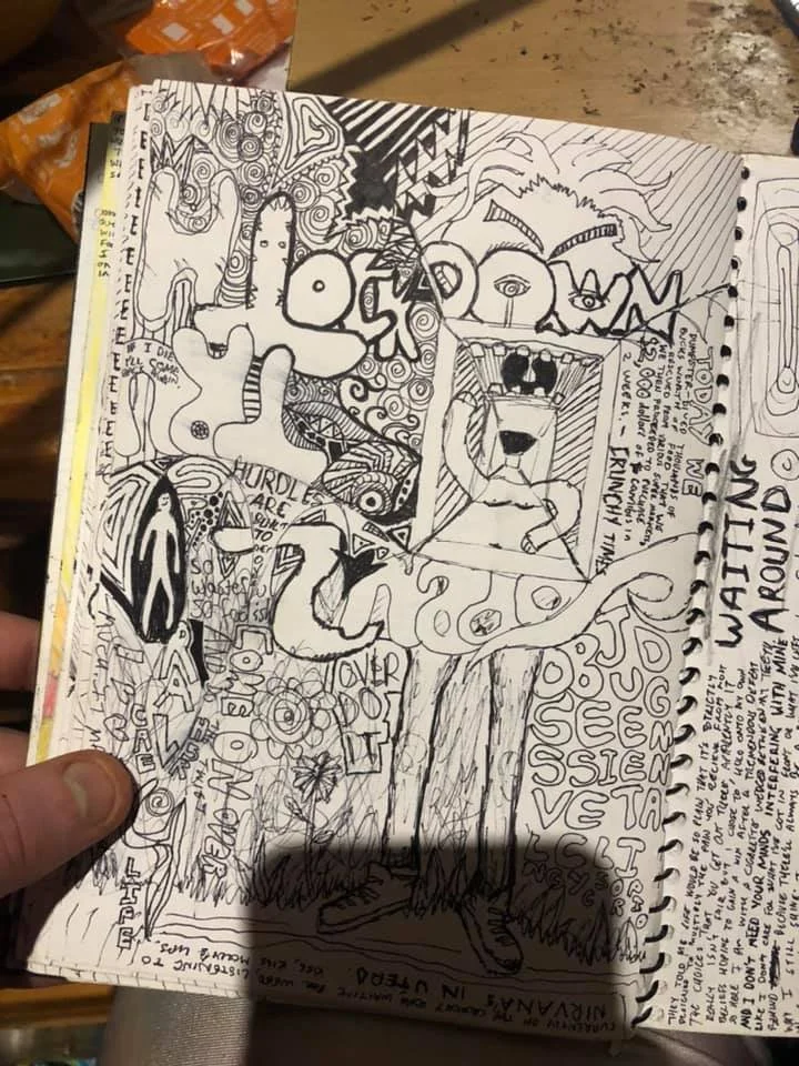 Black and white sketchbook page filled with various doodles, abstract designs, and text, including a large dog in the center, faces, and words like "WATER" and "LOVE".