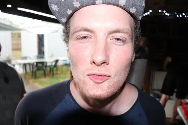 A young man wearing a patterned cap making a kissy face at the camera.