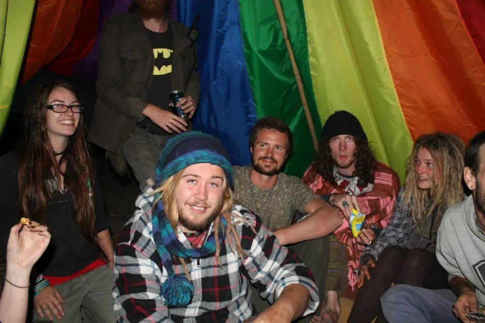 Group of young friends sitting inside a colorful tent, smiling and relaxing.