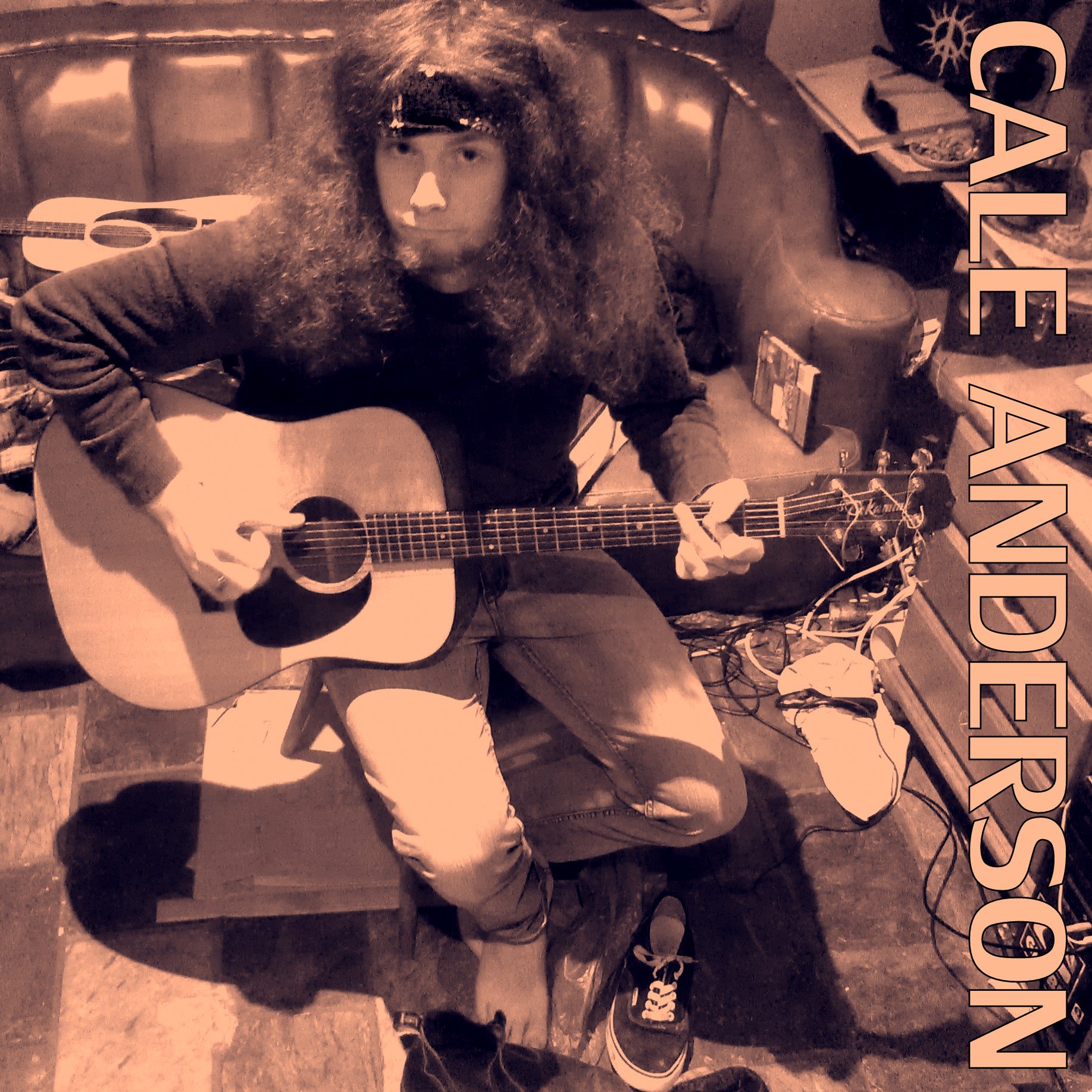 A person with long curly hair and casual clothing playing an acoustic guitar sitting on a chair in a cluttered room. The words 'CALE ANDERSON' are written vertically on the right side.