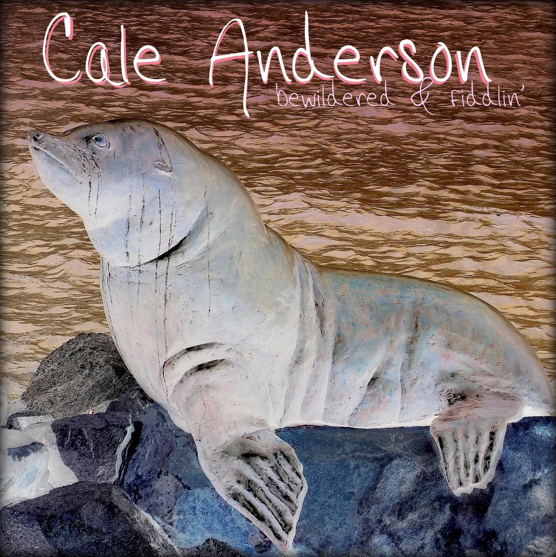 A large sculpture of a seal resting on rocks by the water with pink text reading 'Cale Anderson, bewildered & fiddlin''. 