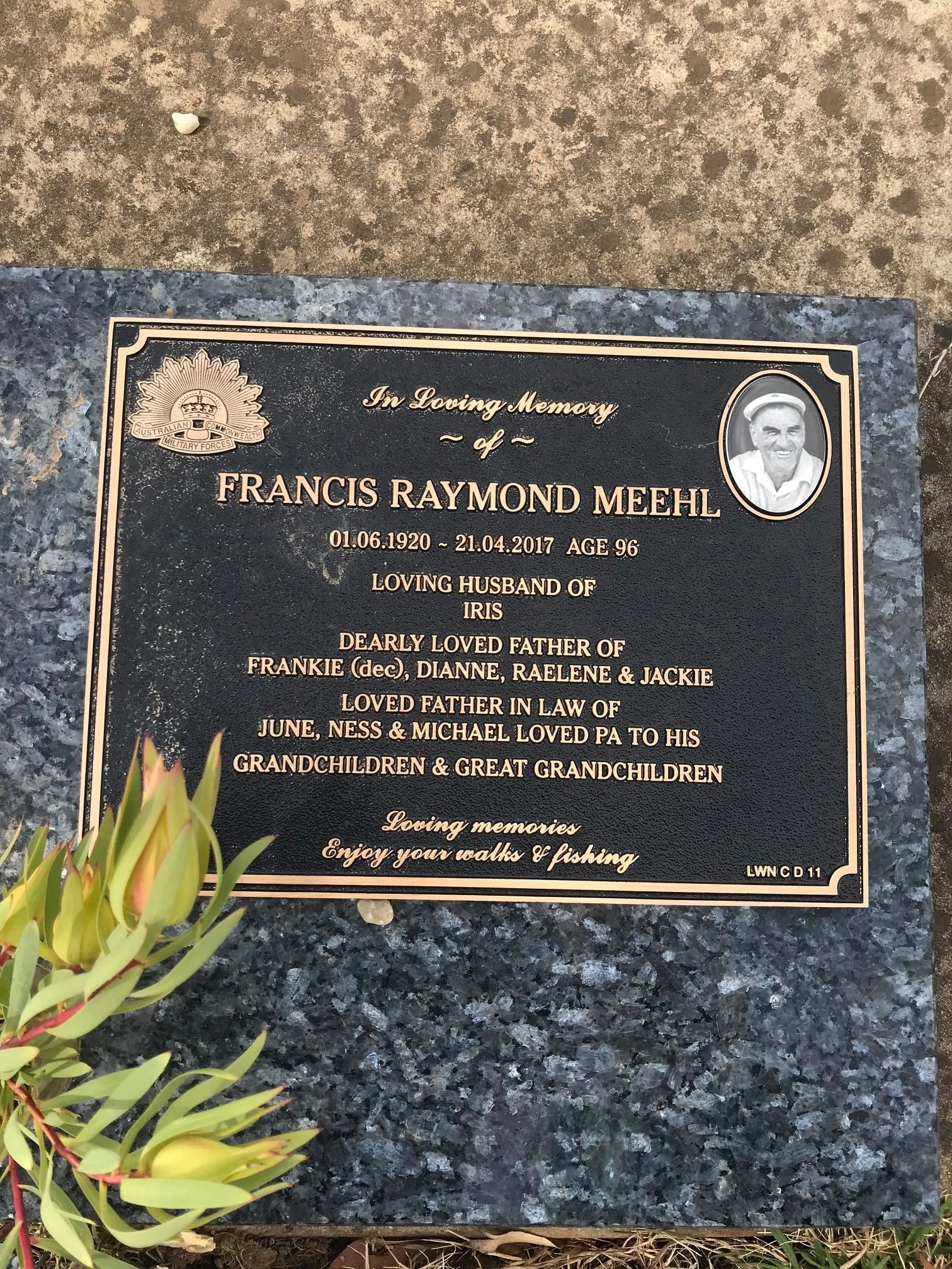 Black memorial plaque with gold lettering and a photo of a smiling man in an oval frame, situated on a stone base. The plaque is dedicated to Francis Raymond Meehl, who was born June 1, 1920, and passed away April 21, 2017, at age 96. It mentions he 