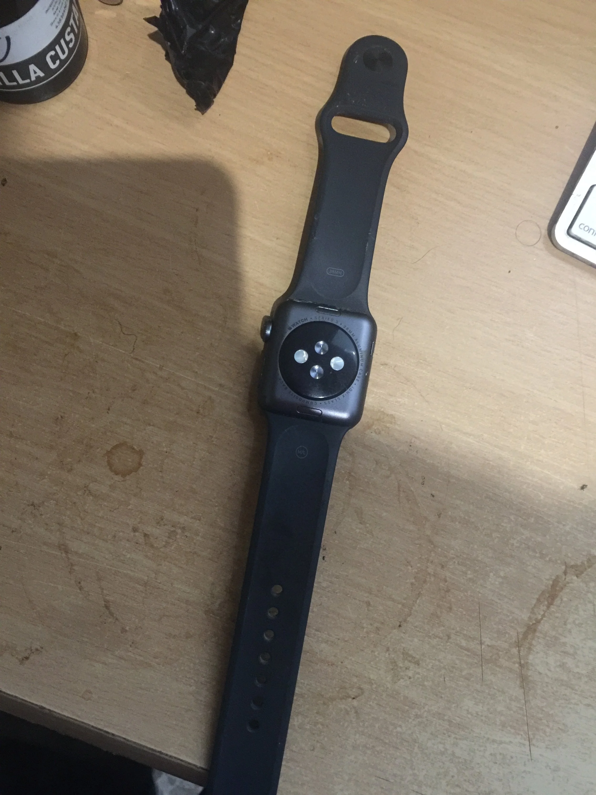Black smartwatch with an empty watch face resting on a wooden desk.
