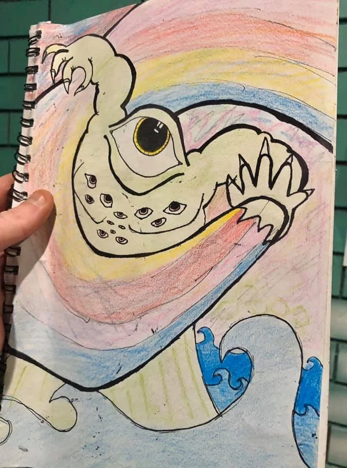 Colorful drawing of a creature with multiple eyes, a big single eye, claws, and a tail, set against a vibrant background with waves at the bottom.