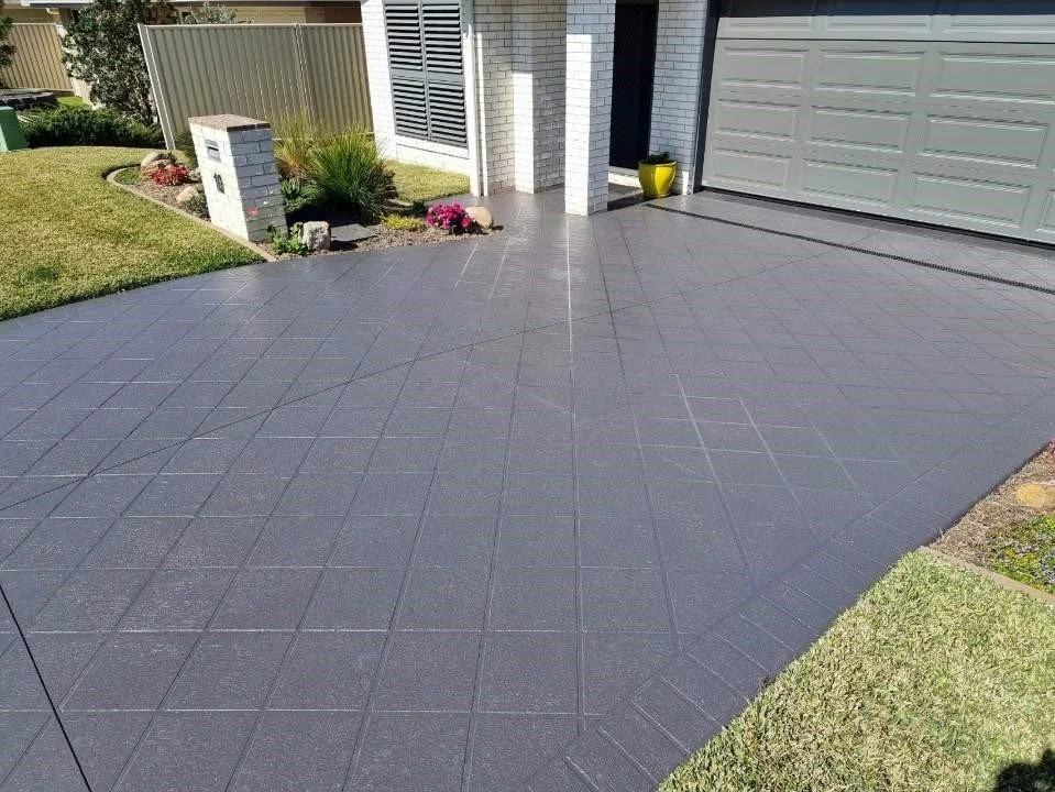 A grey concrete driveway, featuring a sealed surface that enhances its durability and protects it from potential damage.