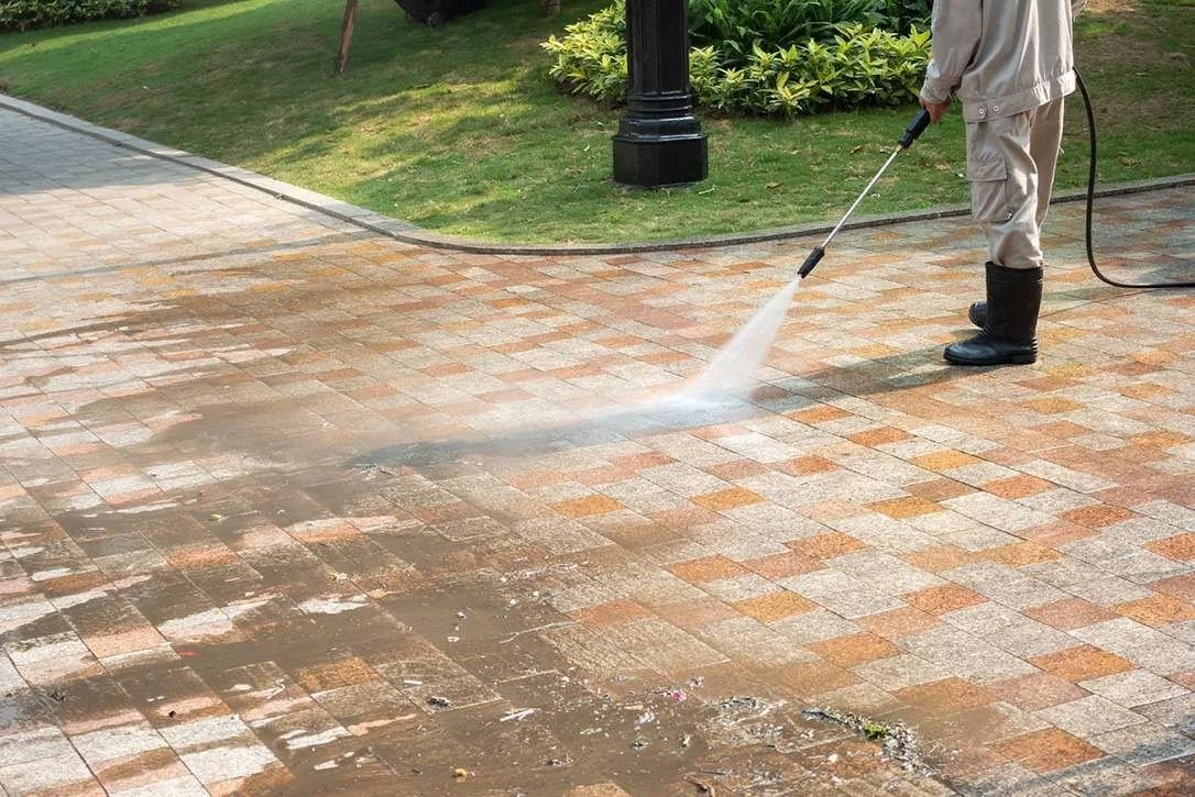 Professional pressure washing of a paved driveway, effectively removing dirt and grime to restore the surface’s original appearance, showcasing Titan Pressure Pros' expert exterior cleaning services.