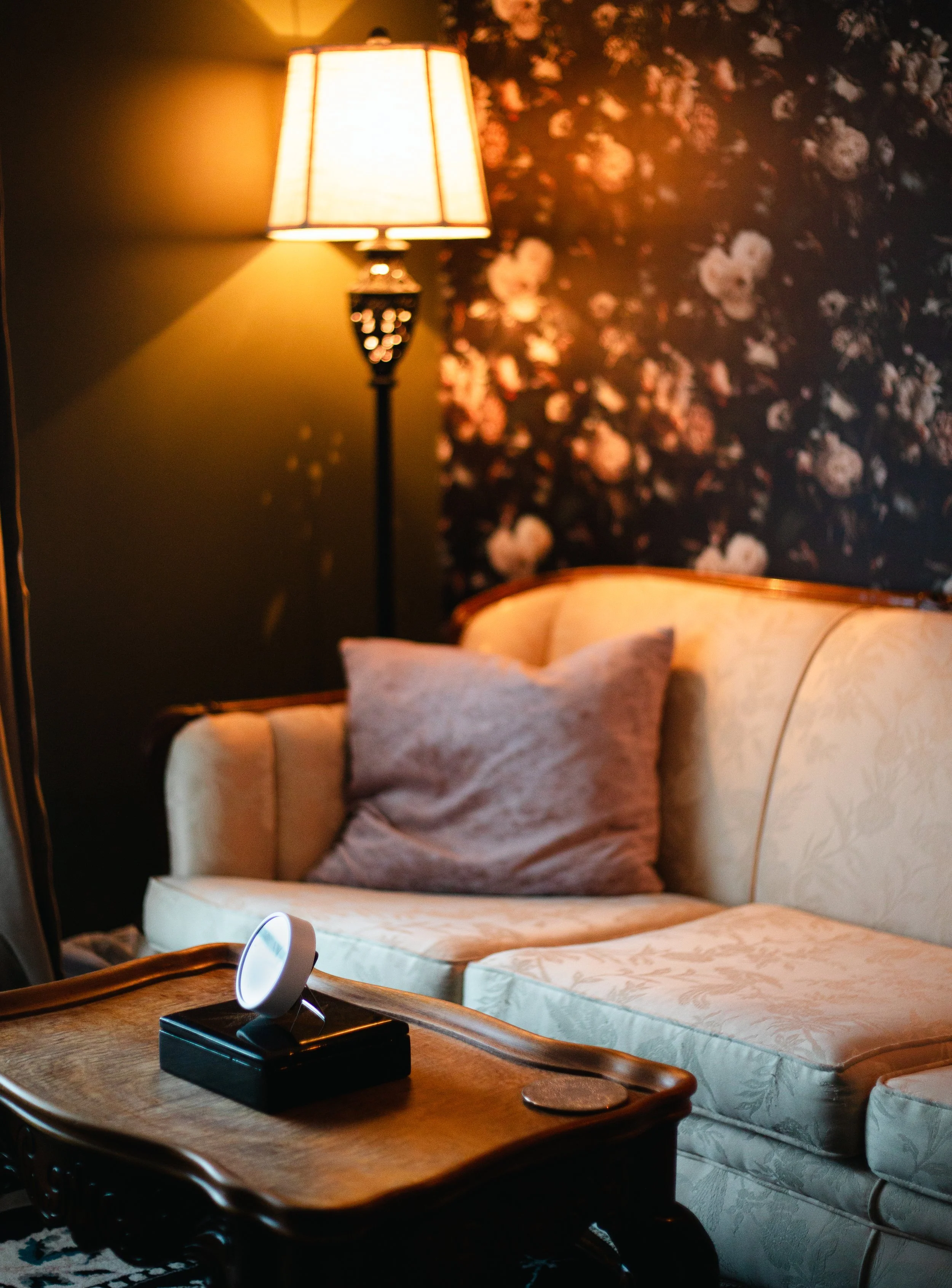 Warm, private clinical counselling space with a vintage loveseat and floral wallpaper at The Den Wellness Collective in Vancouver