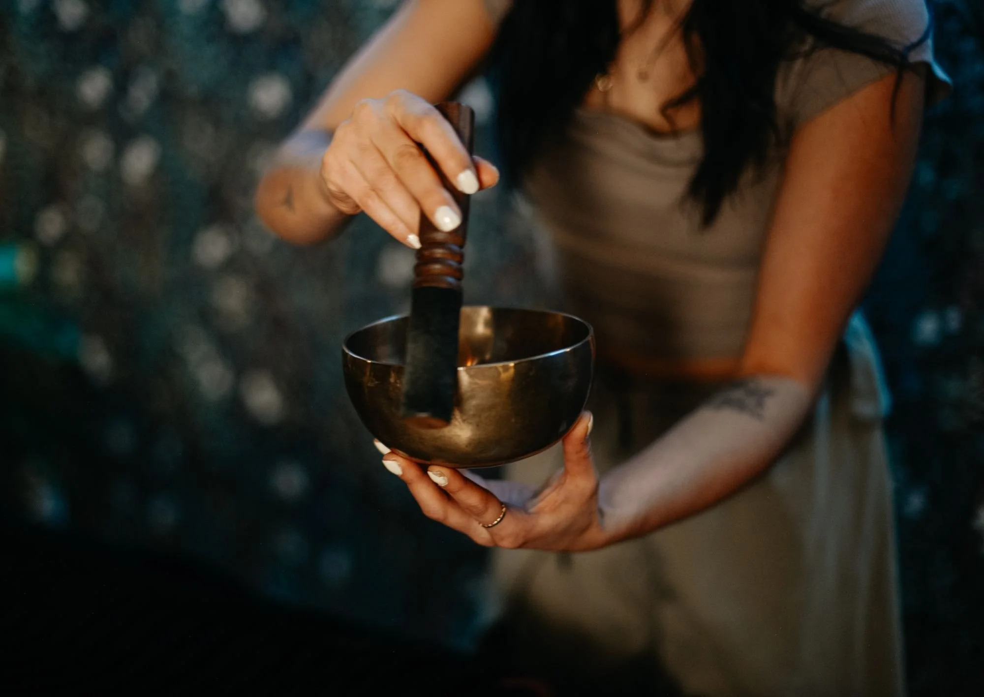 Sound therapist playing a Tibetan singing bowl at The Den Wellness Collective in Vancouver
