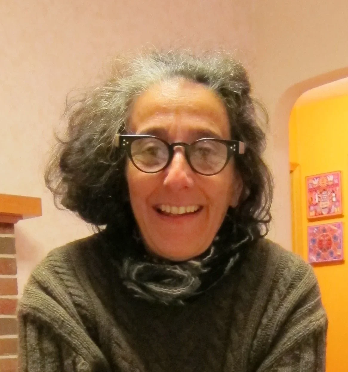 A woman with curly gray hair and glasses smiling at the camera.