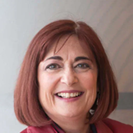 Close-up of a smiling woman with shoulder-length red hair, wearing a red blazer.