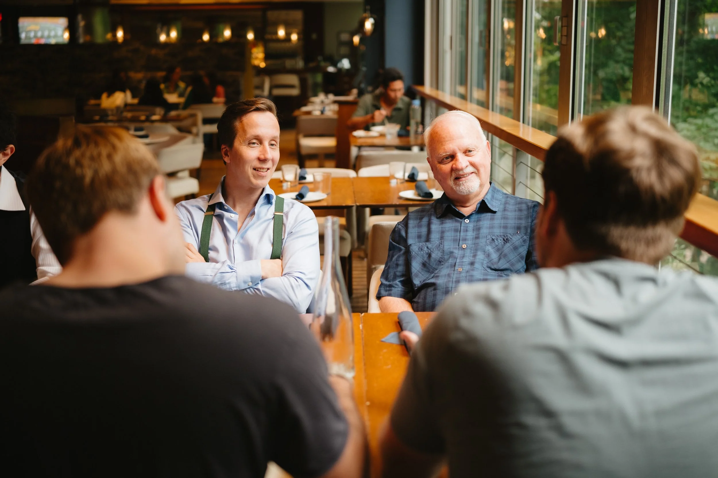 Group of people having a meeting in a modern restaurant with natural light from large windows.