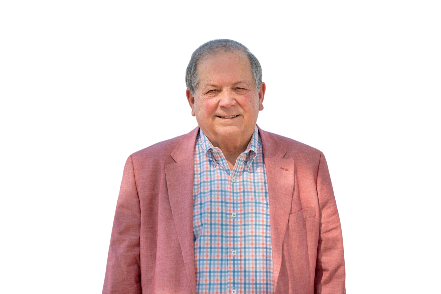 A middle-aged man in a black suit, blue shirt, and patterned tie, smiling, with a small American flag pin on his lapel.