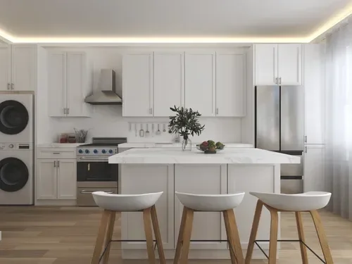 Modern white kitchen with a marble island, three white barstools with wooden legs, white cabinetry, stainless steel appliances including a fridge, oven, and hood, a vase with greenery, and a bowl of fruit on the island.