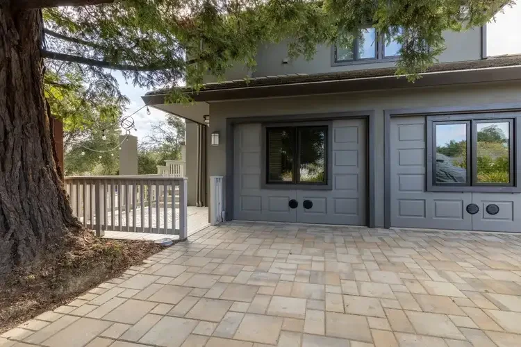 Attached One Bedroom Garage Conversion ADU in residential exterior with stone patio surrounded by trees.