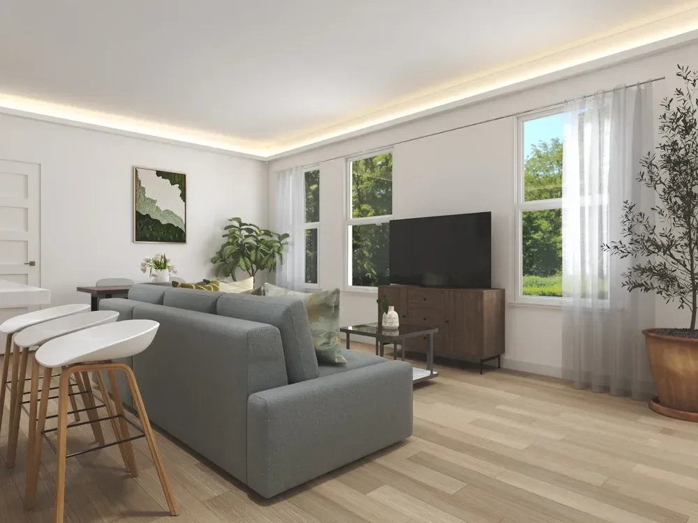 Backyard ADU Modern living room with gray sofa, wooden floor, large TV, coffee table, bar stools, indoor plants, and large windows with sheer curtains.