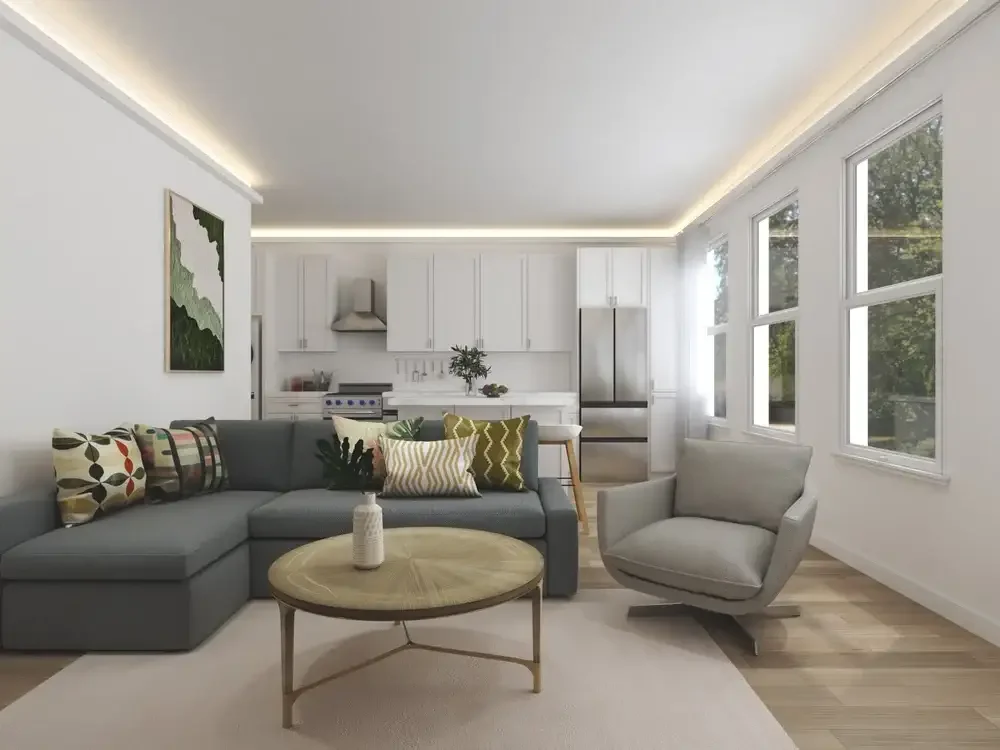 Backyard ADU Modern living room with gray sectional sofa, patterned cushions, round wooden coffee table, and swivel armchair; adjacent white kitchen with stainless steel appliances, and large windows with outdoor view.