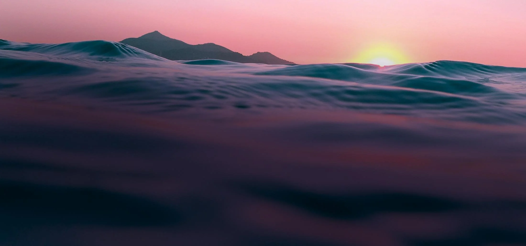 Soft waves in the ocean at sunset showing colours of orange and purple as the sun goes down