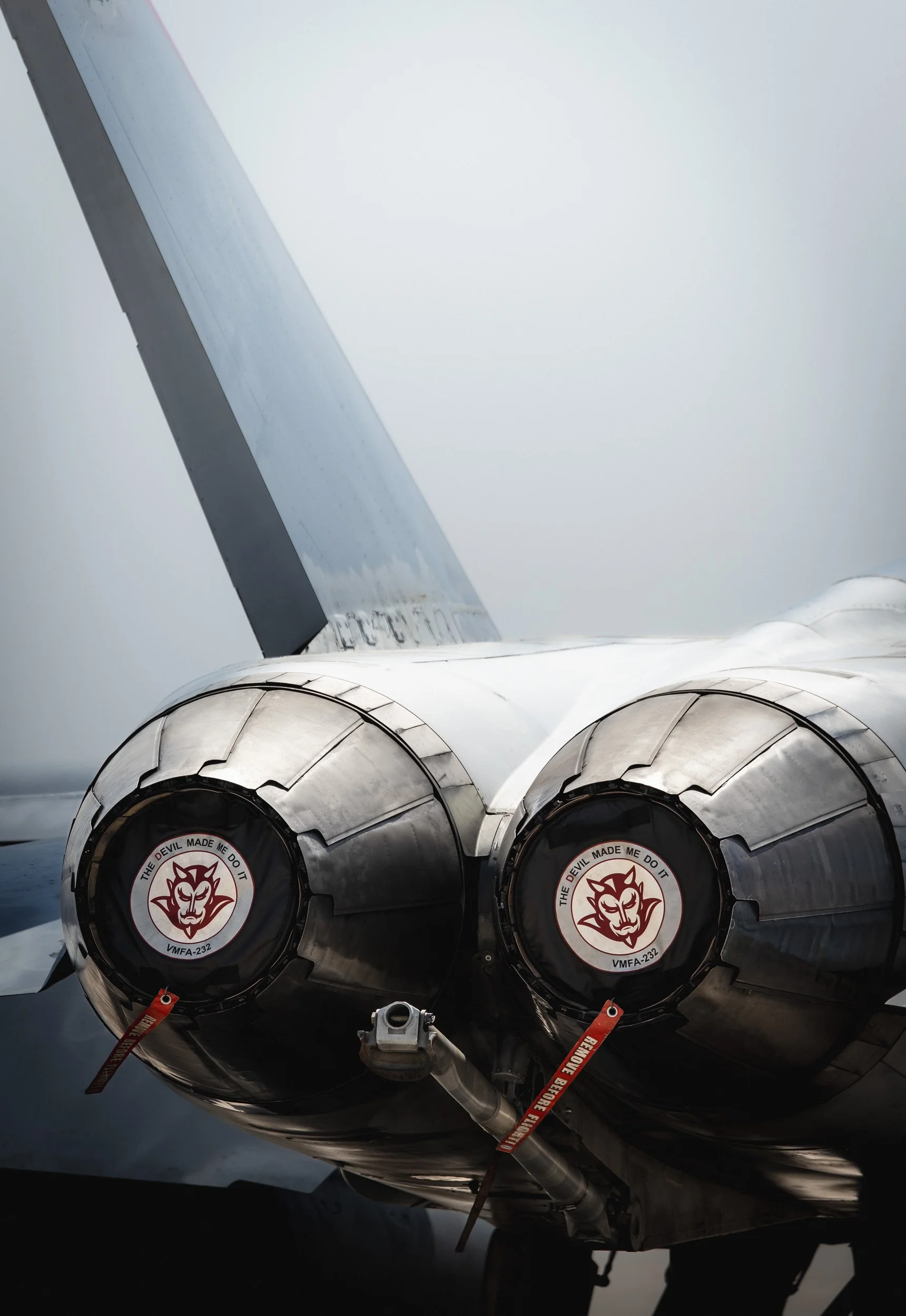 The rear of a military jet aircraft engine with a logo of a devil's face and the words 'The devil made me do it' on the engine covers.