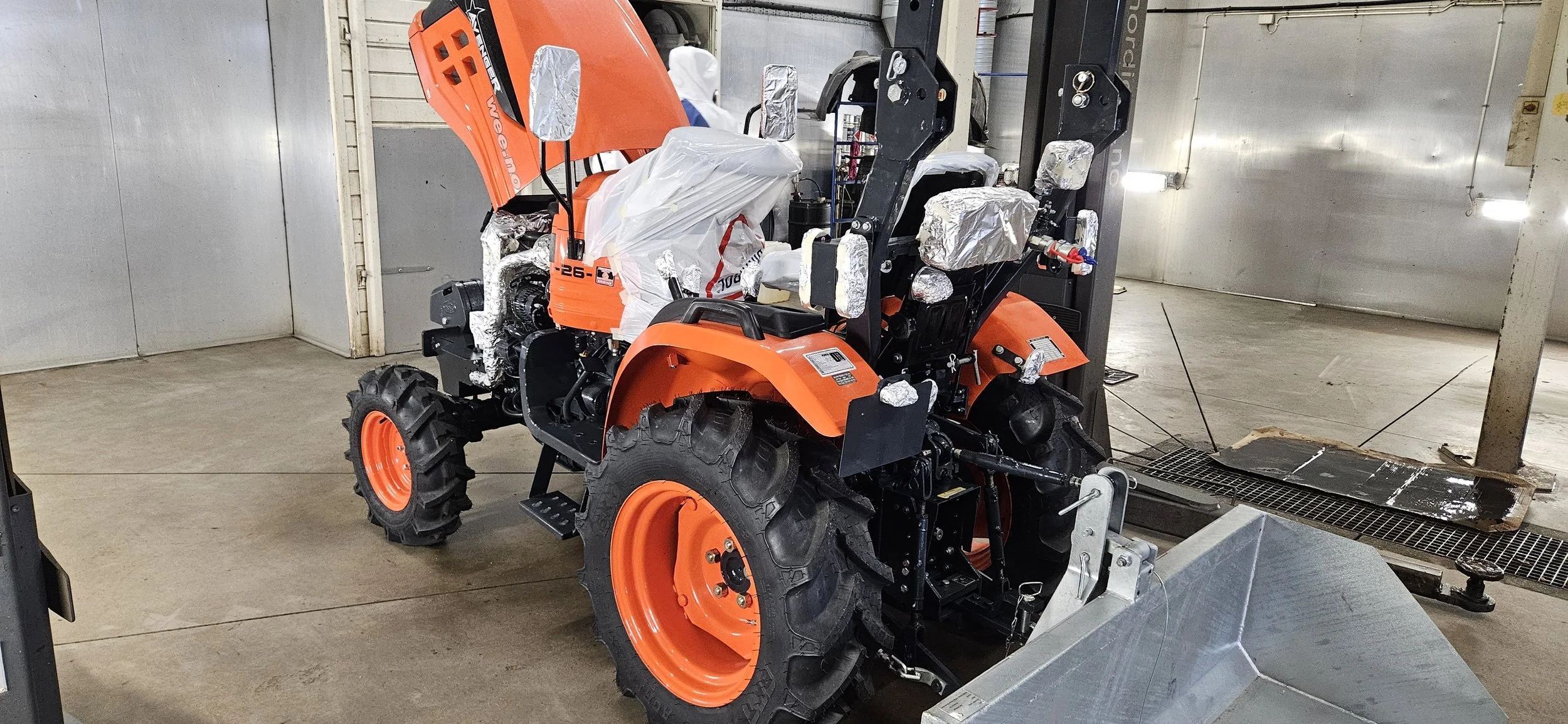 En orange traktor som er klargjort for å bli behandles med Dinitrol rustbeskyttelse
