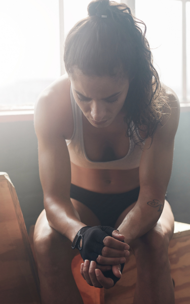 Athlete sitting with her head down, wrapping her hands before training